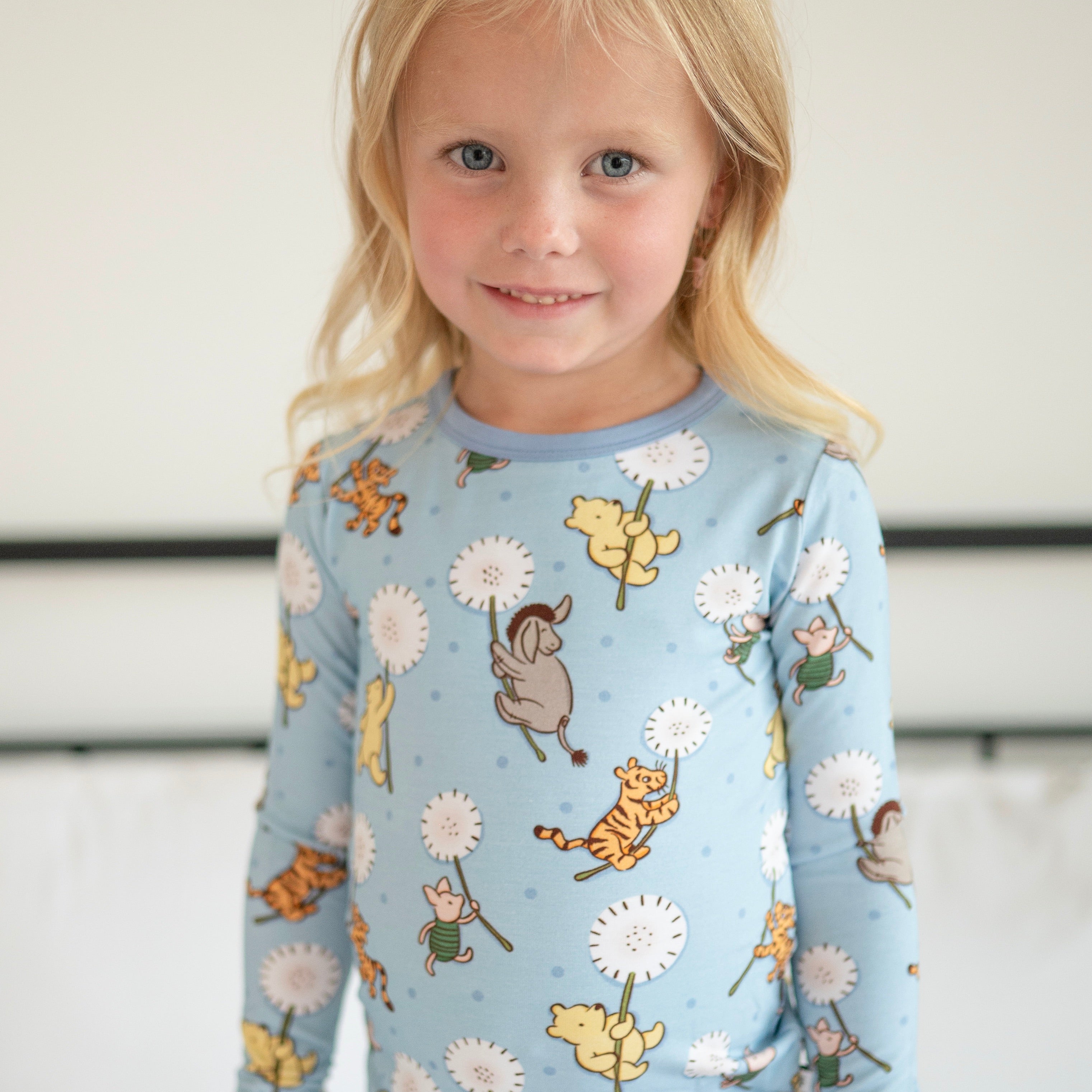A young girl smiles wearing a light blue long-sleeved pajama top