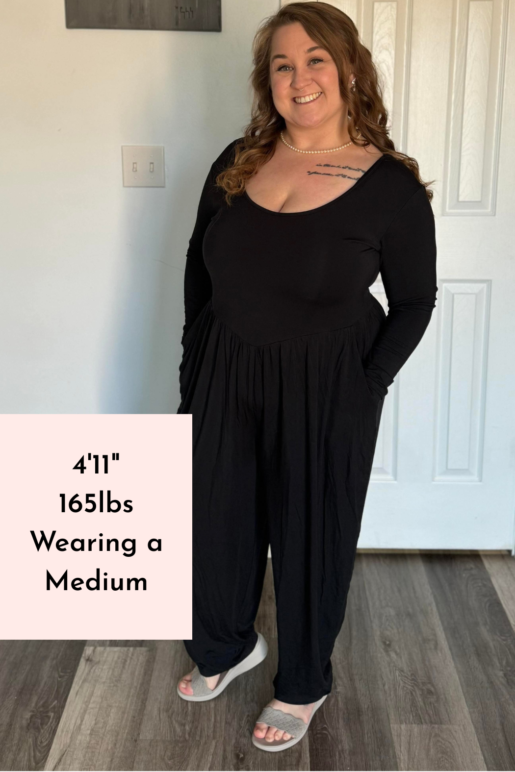 A woman wears a long-sleeve black Tencel Modal romper with a scoop neck and tapered legs.