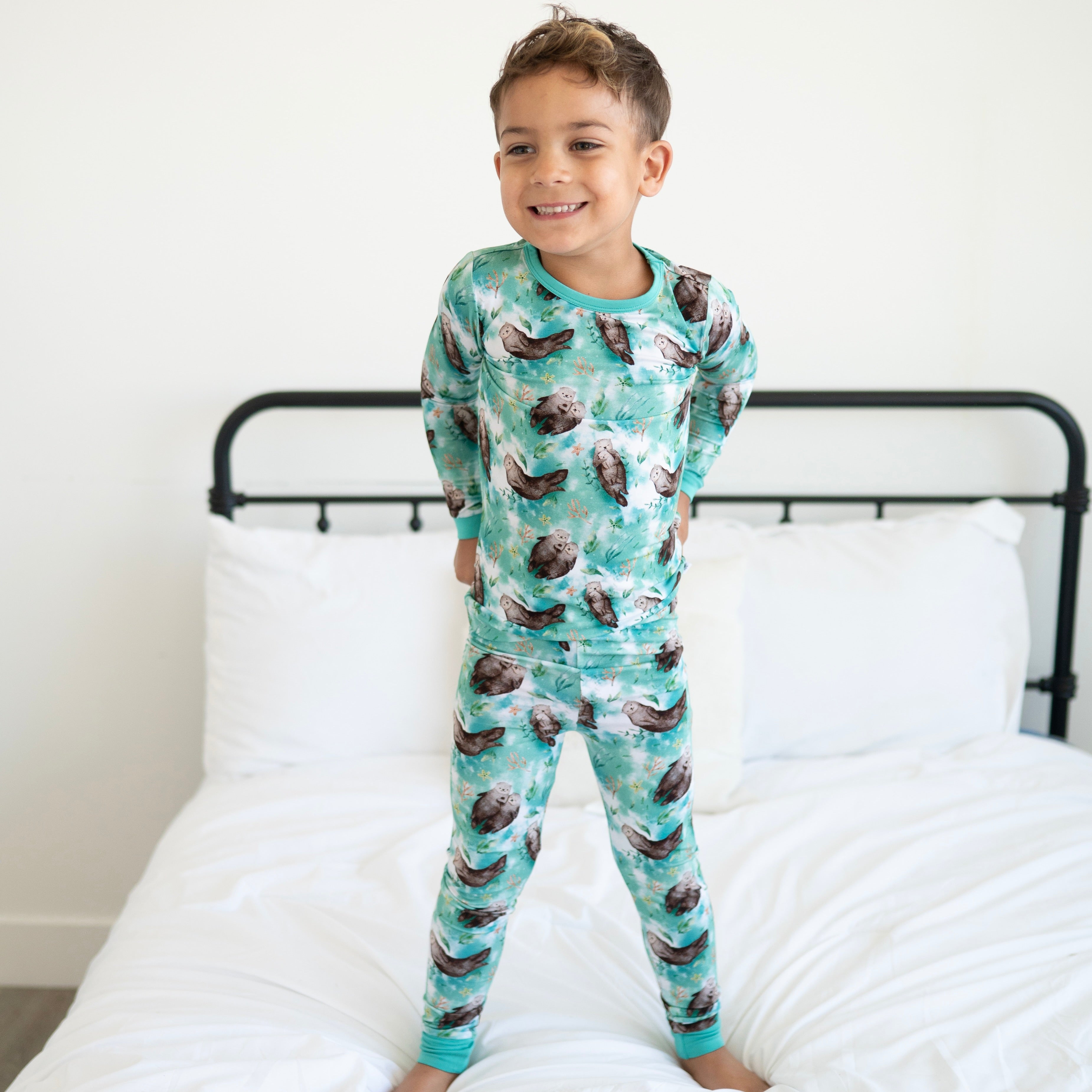 A young boy wears a teal pajama set with an otter print.