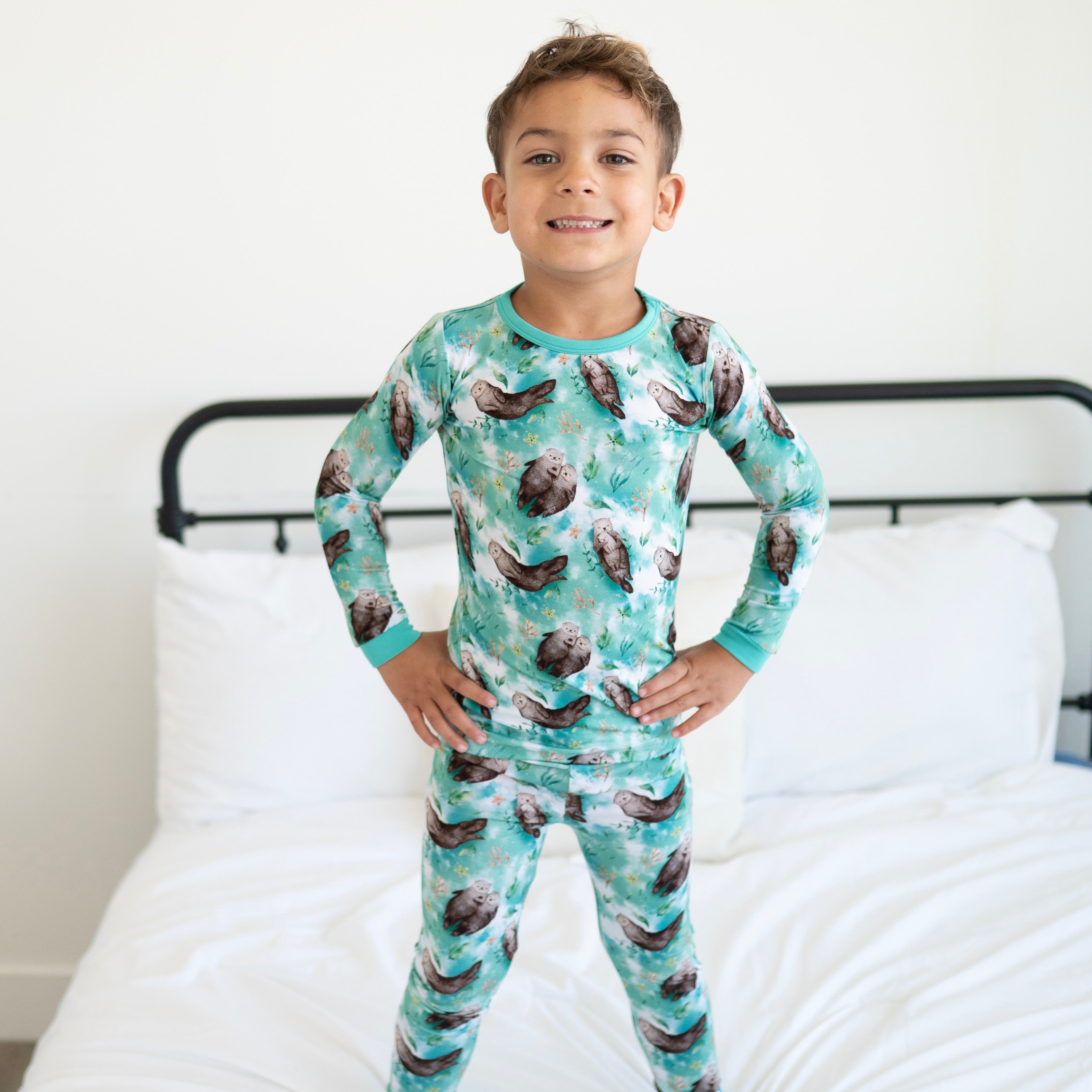 A young boy wears a teal pajama set with an otter print.