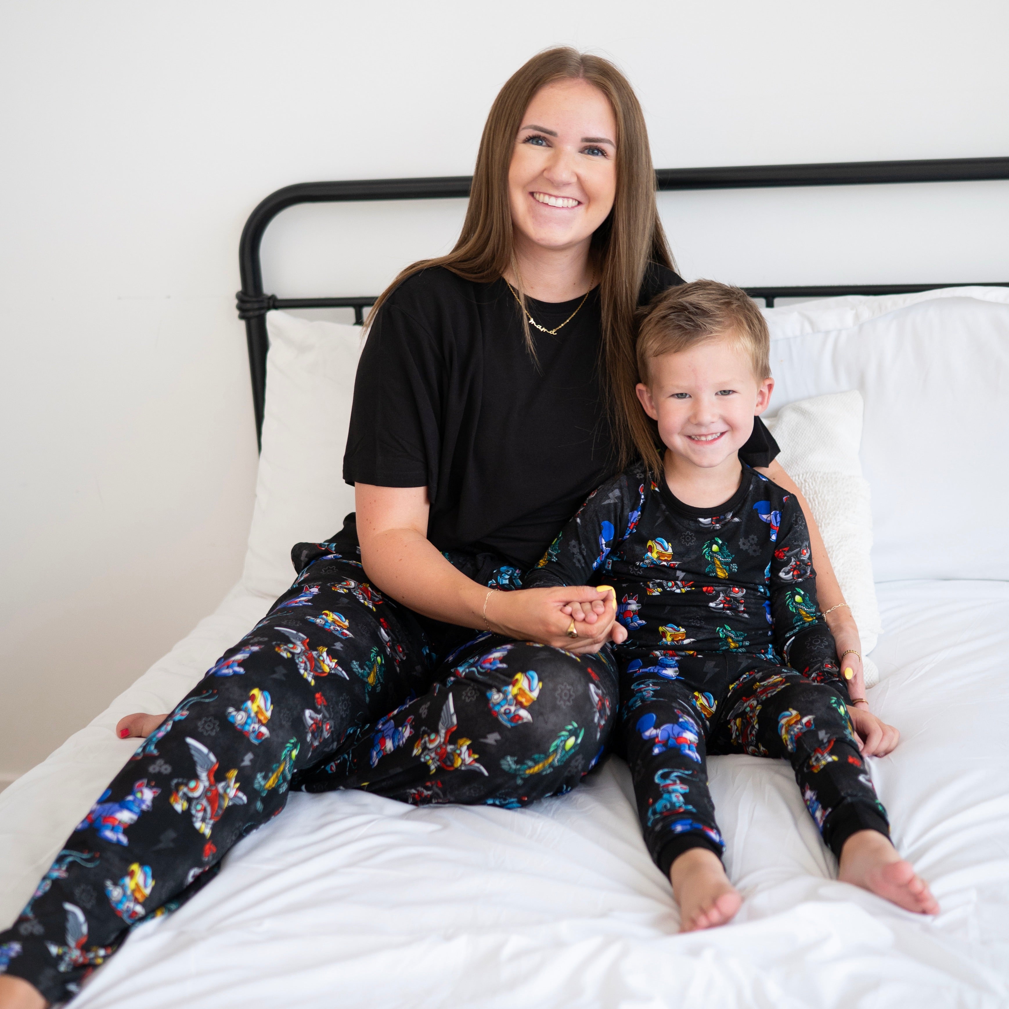 A woman and child in matching black pajamas with a Neopets robot print.