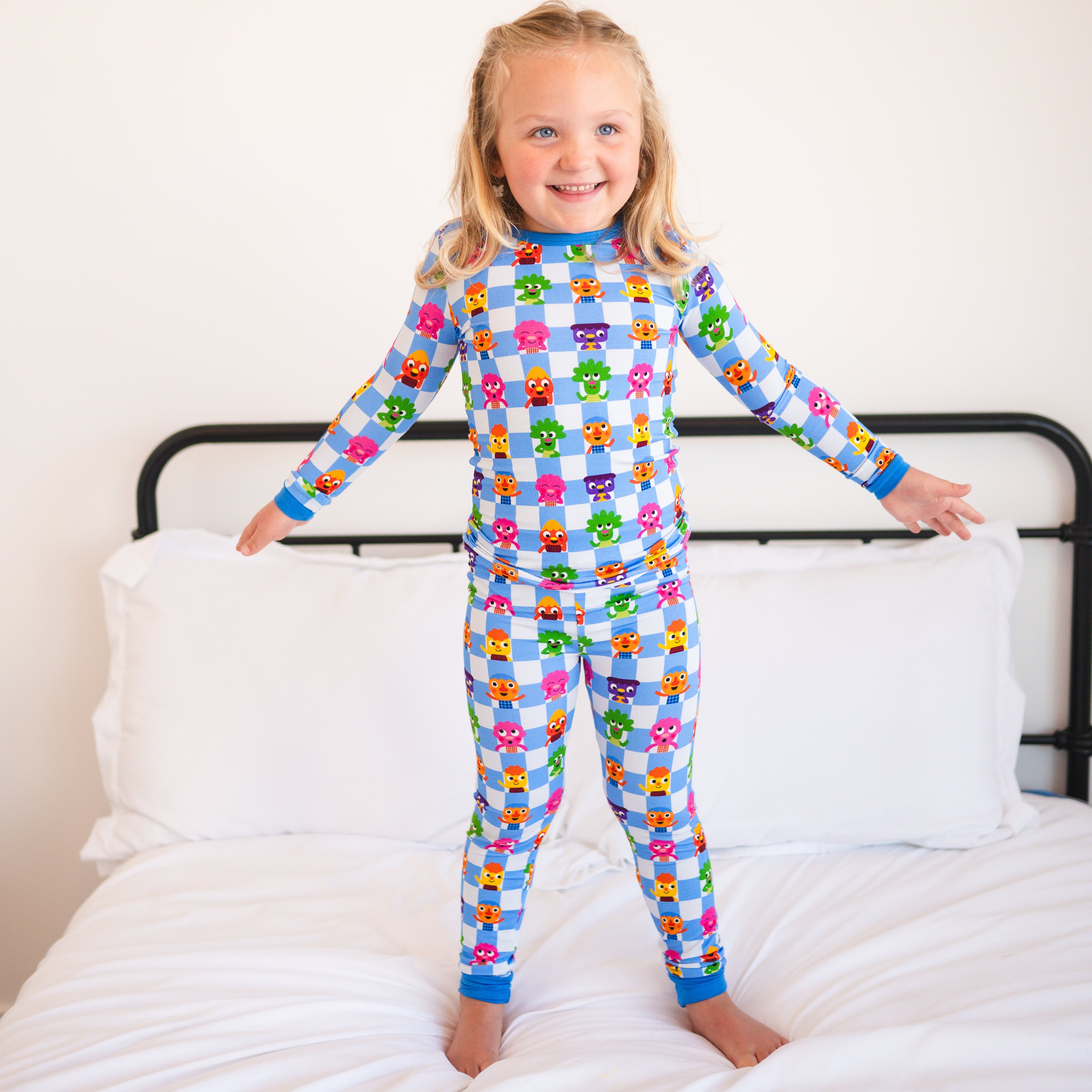 A young girl in blue checkered pajamas with colorful monster characters.