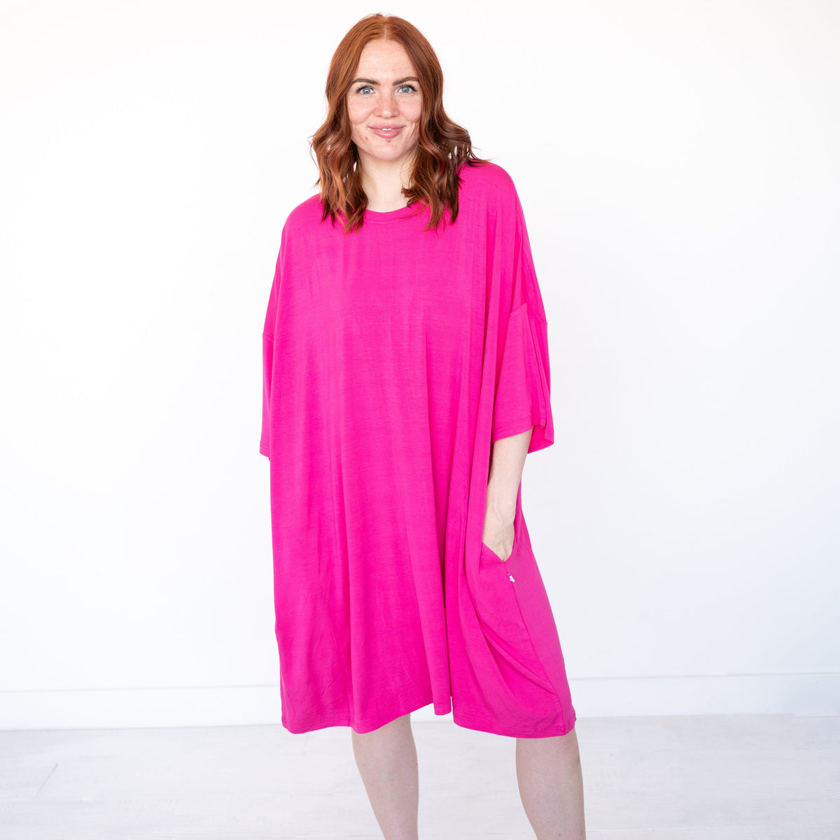 A woman models a loose-fitting, bright pink bamboo sleep tee with pockets.