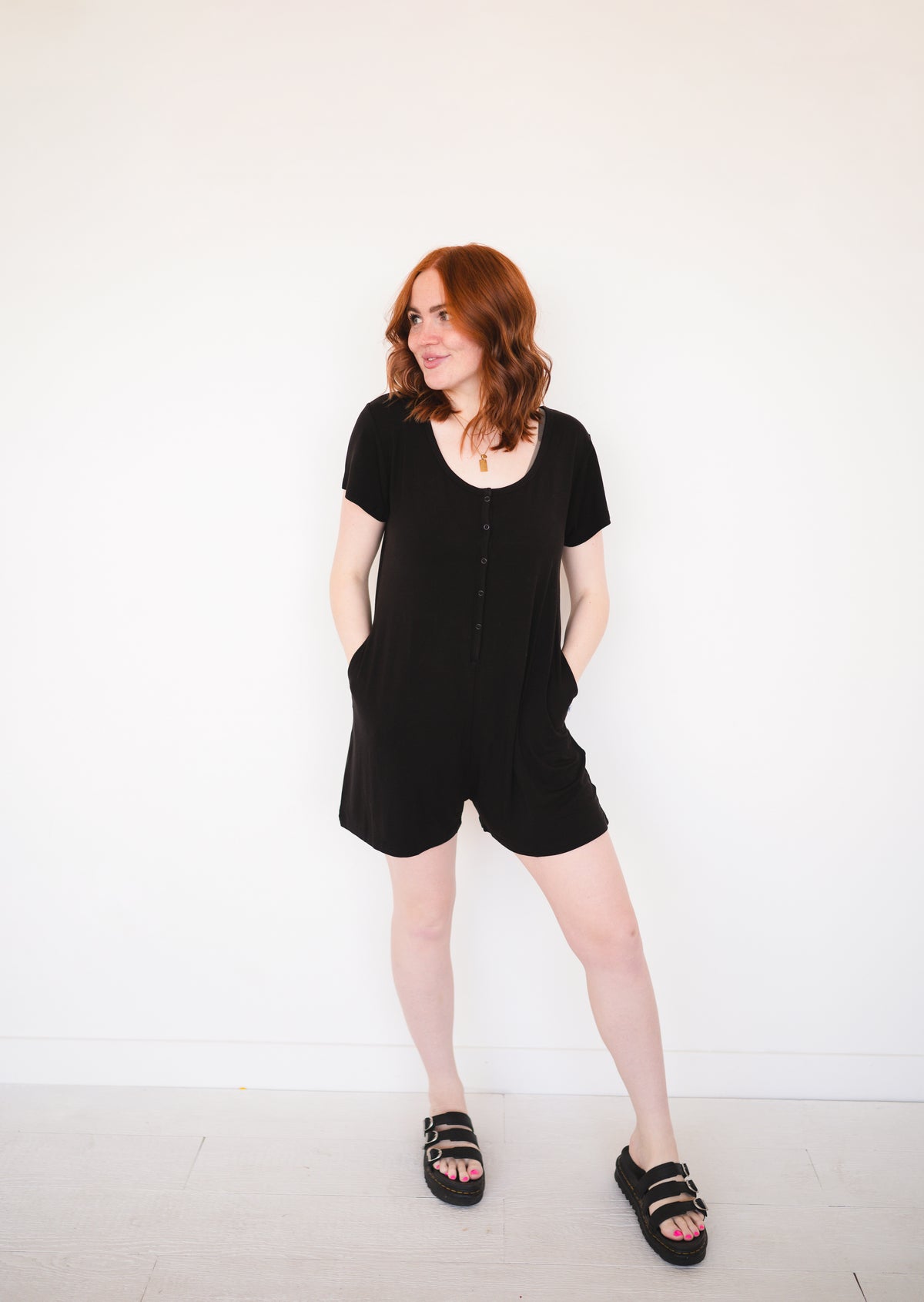 Black short-sleeve romper with button front and pockets.