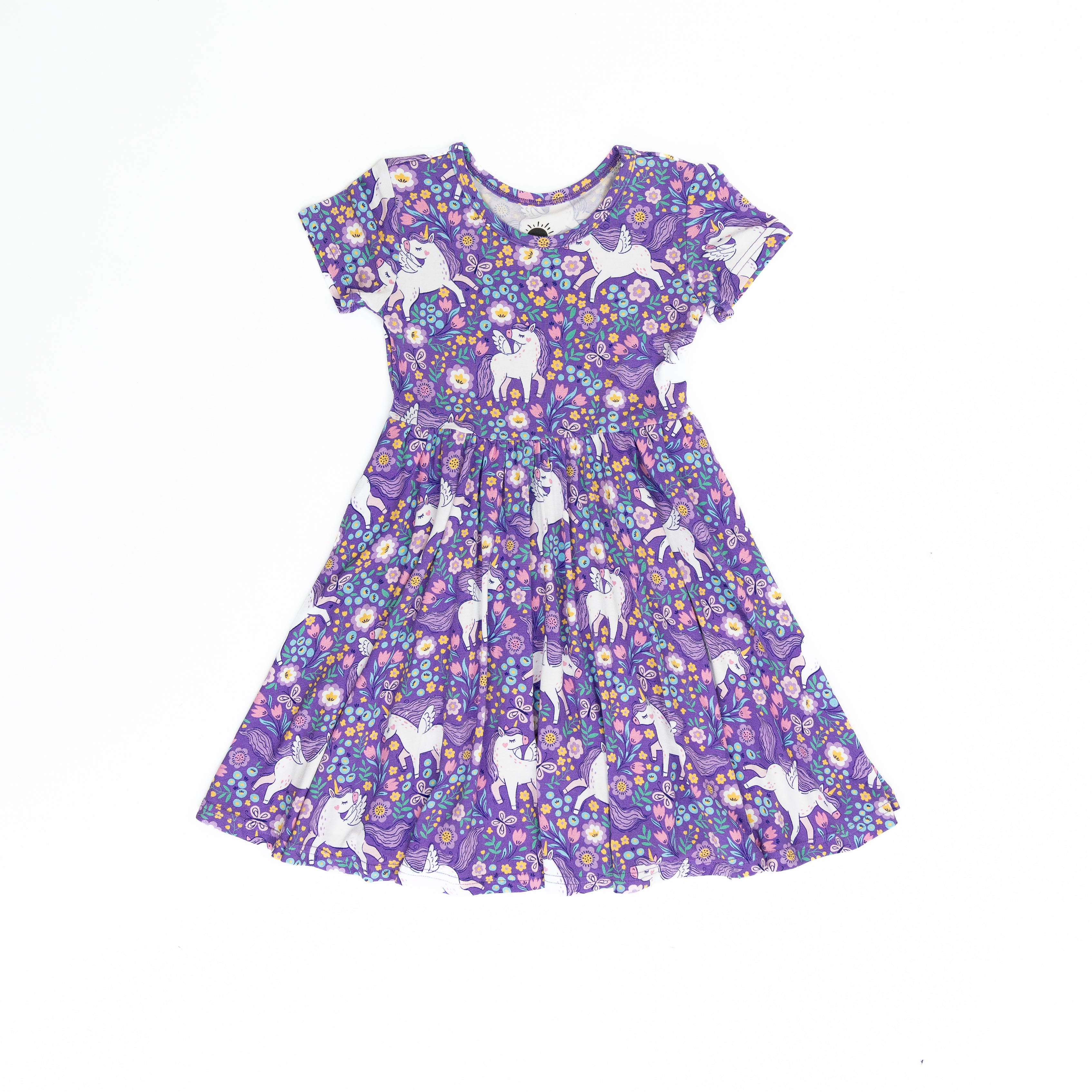 A purple short-sleeved dress featuring a repeating pattern of white unicorns and colorful flowers.