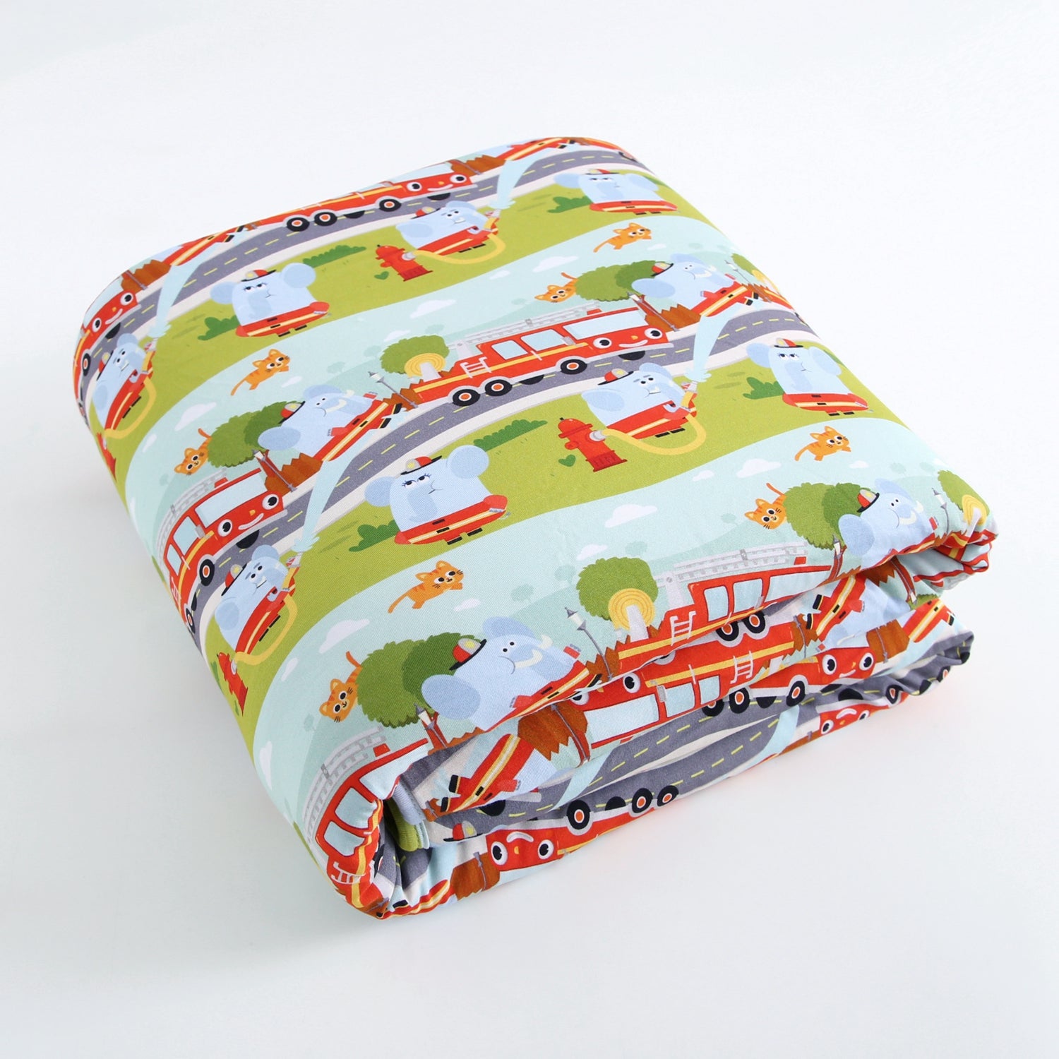 A folded plush blanket with a colorful cartoon print of elephants in fire hats and red firetrucks.