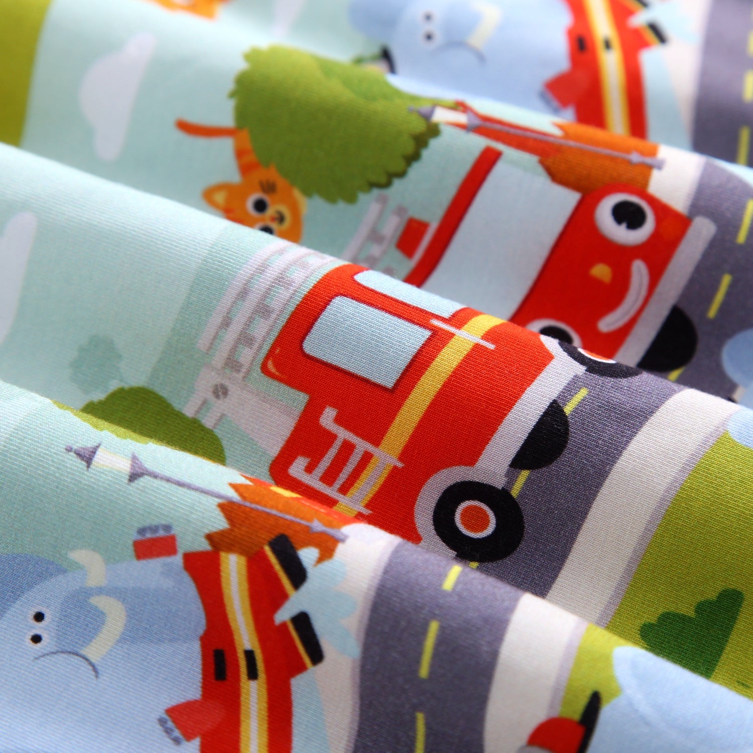 A close-up of a soft fabric with a playful firetruck and animal print.