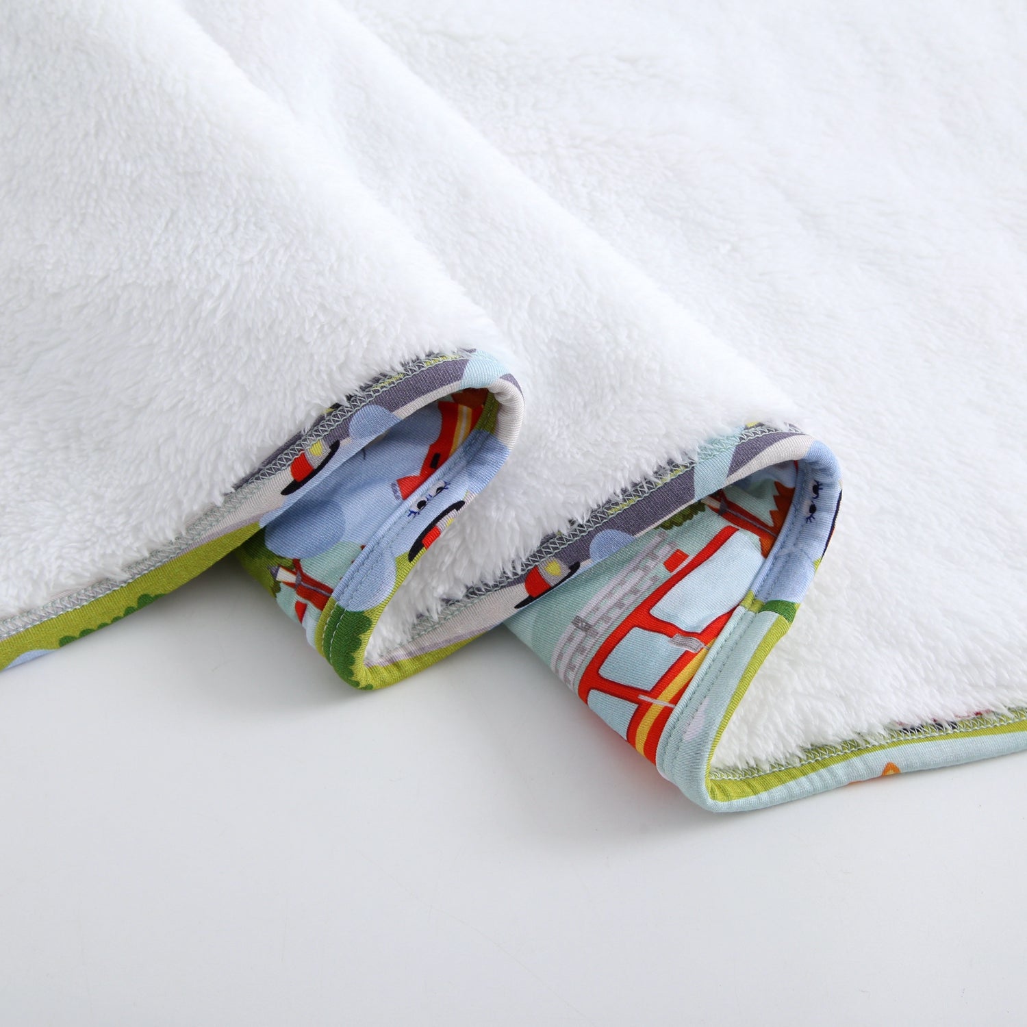 White plush blanket with a firetruck print trim.