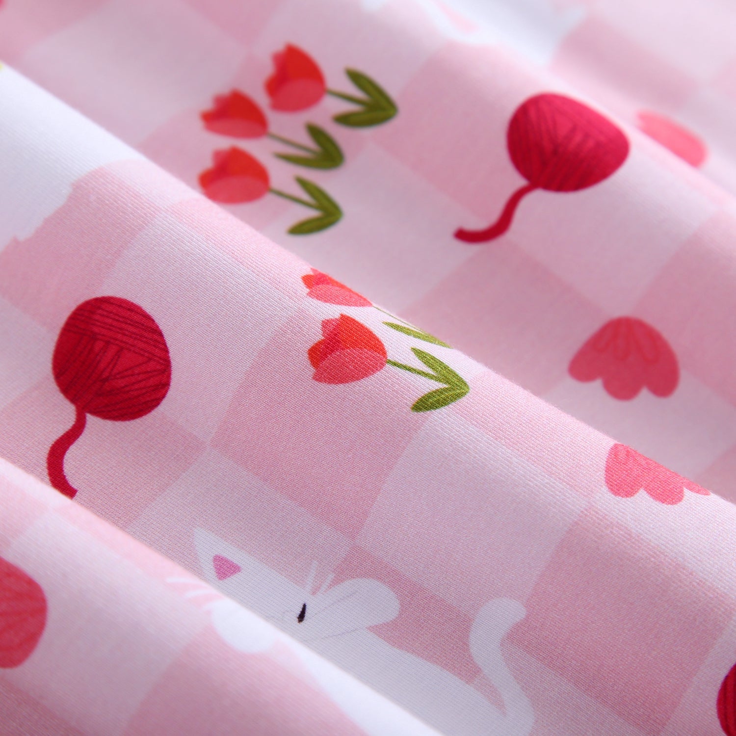 Pink gingham fabric with a pattern of tulips and yarn balls.