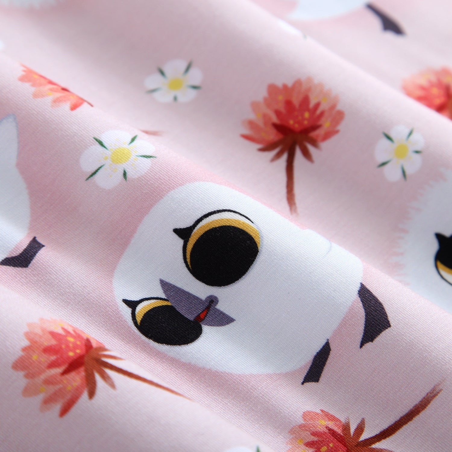 Pink fabric with a pattern of cartoon puffins and flowers.