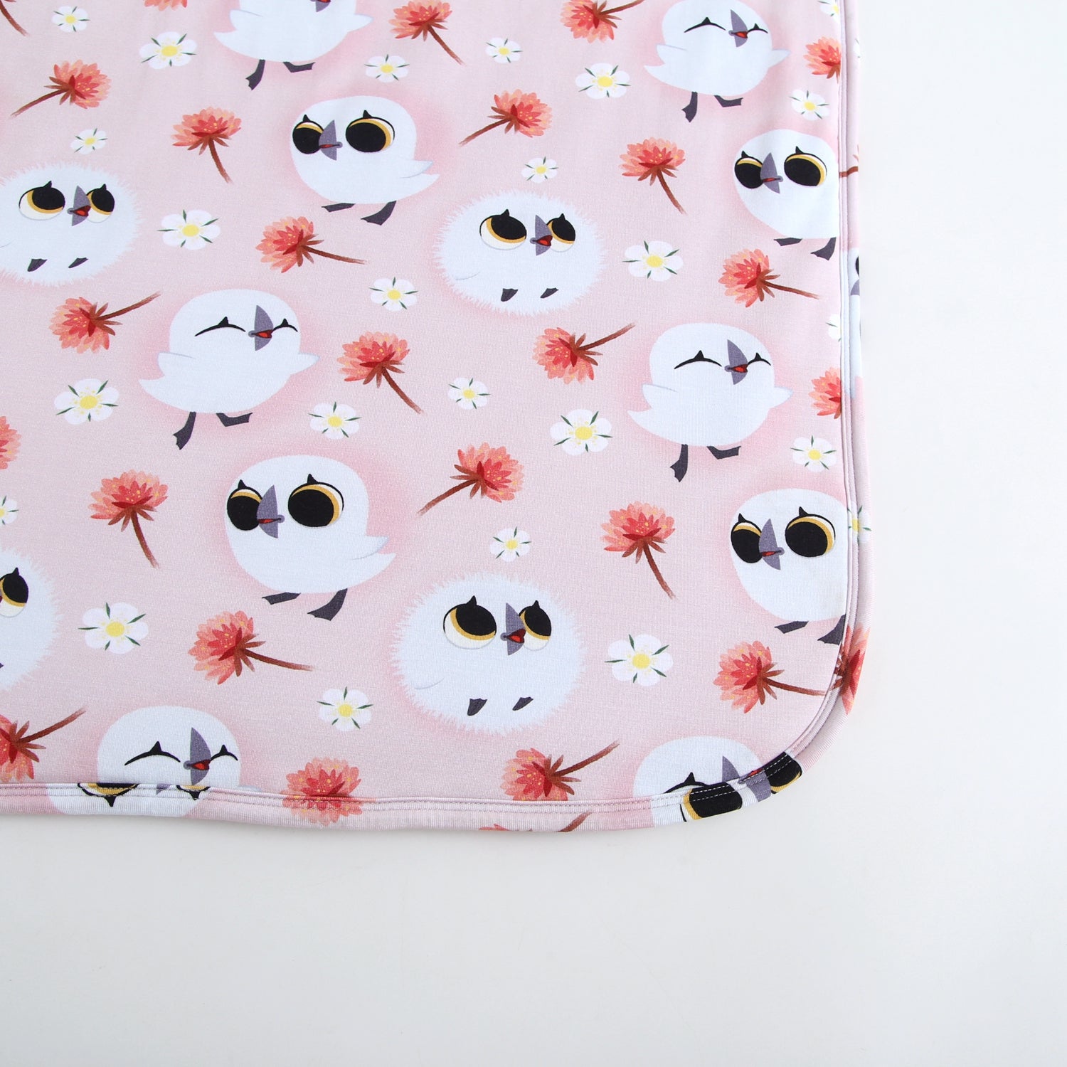 Pink blanket with white puffins and flowers pattern.