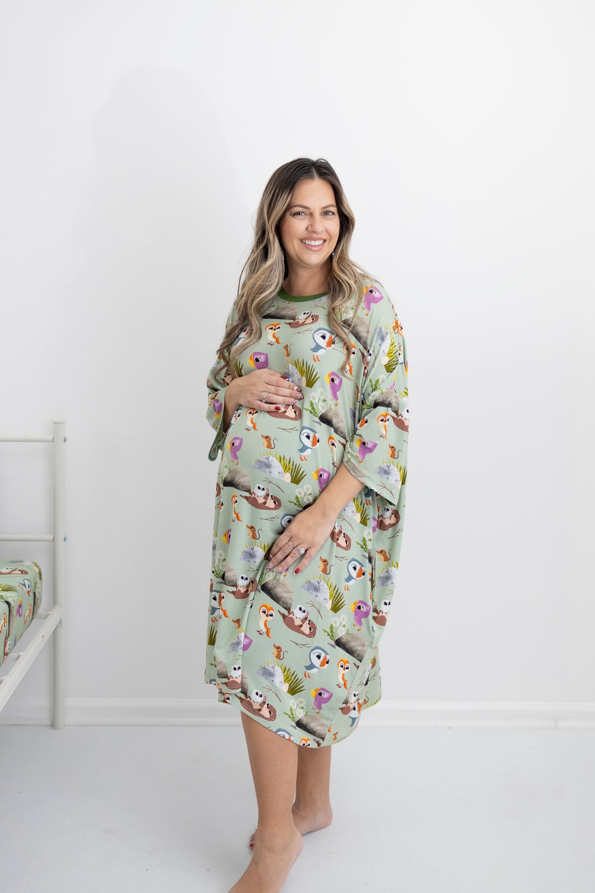 A pregnant woman wears a light green sleep tee with a Puffin Rock™ print.