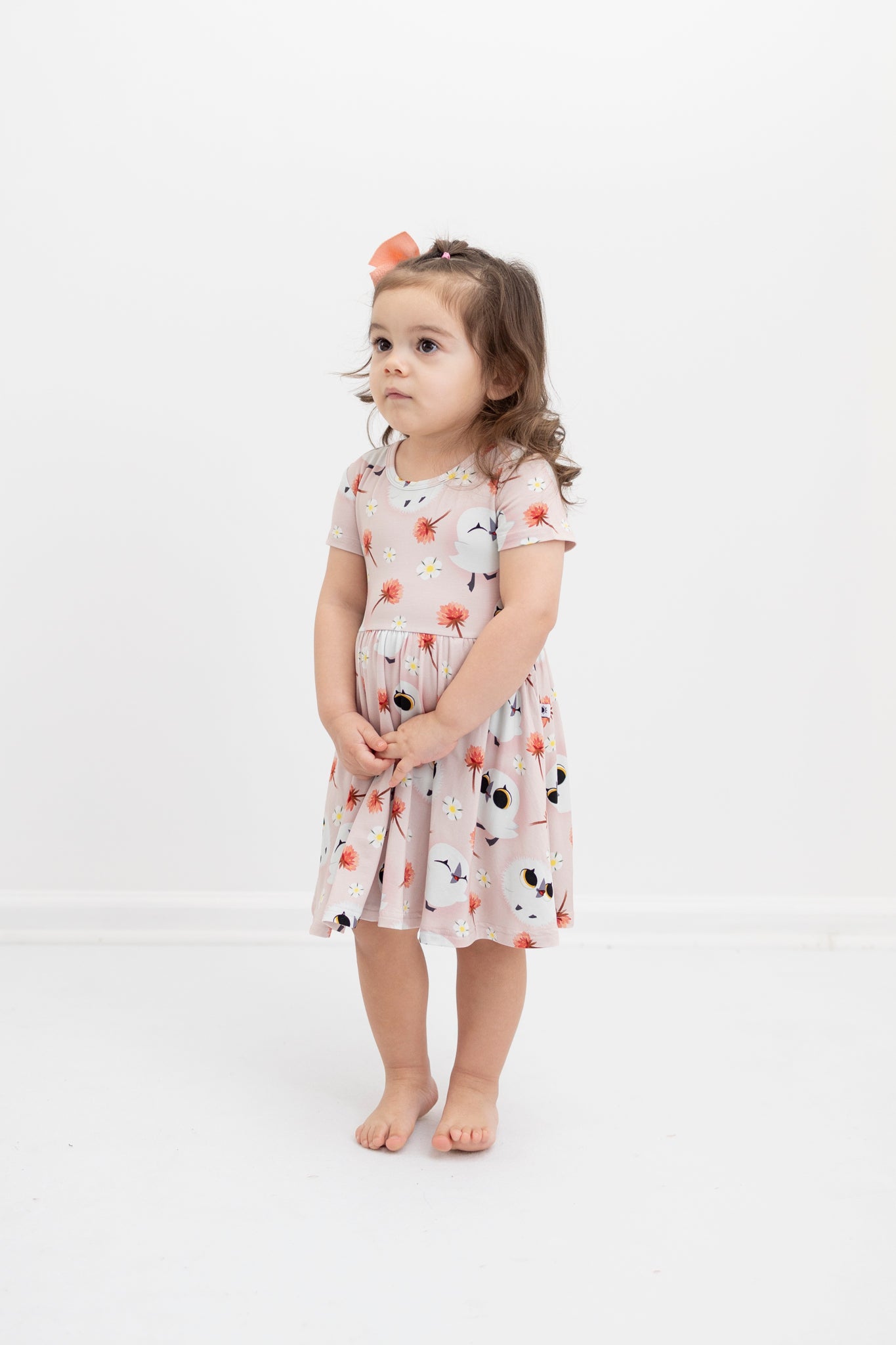 A young girl wears a pink Tencel Modal dress with a puffin print.