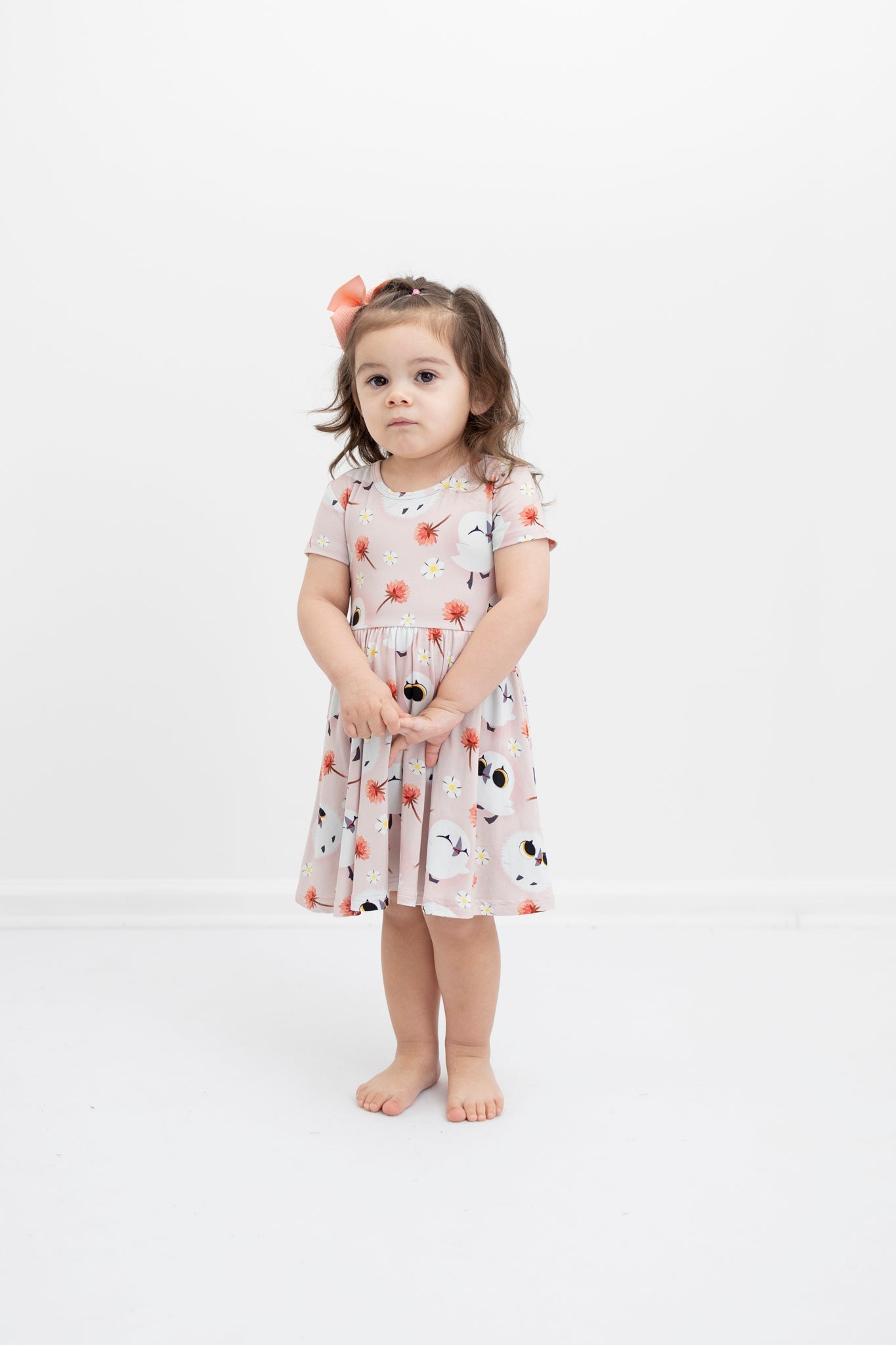 A young girl wears a pink dress with a puffin print.