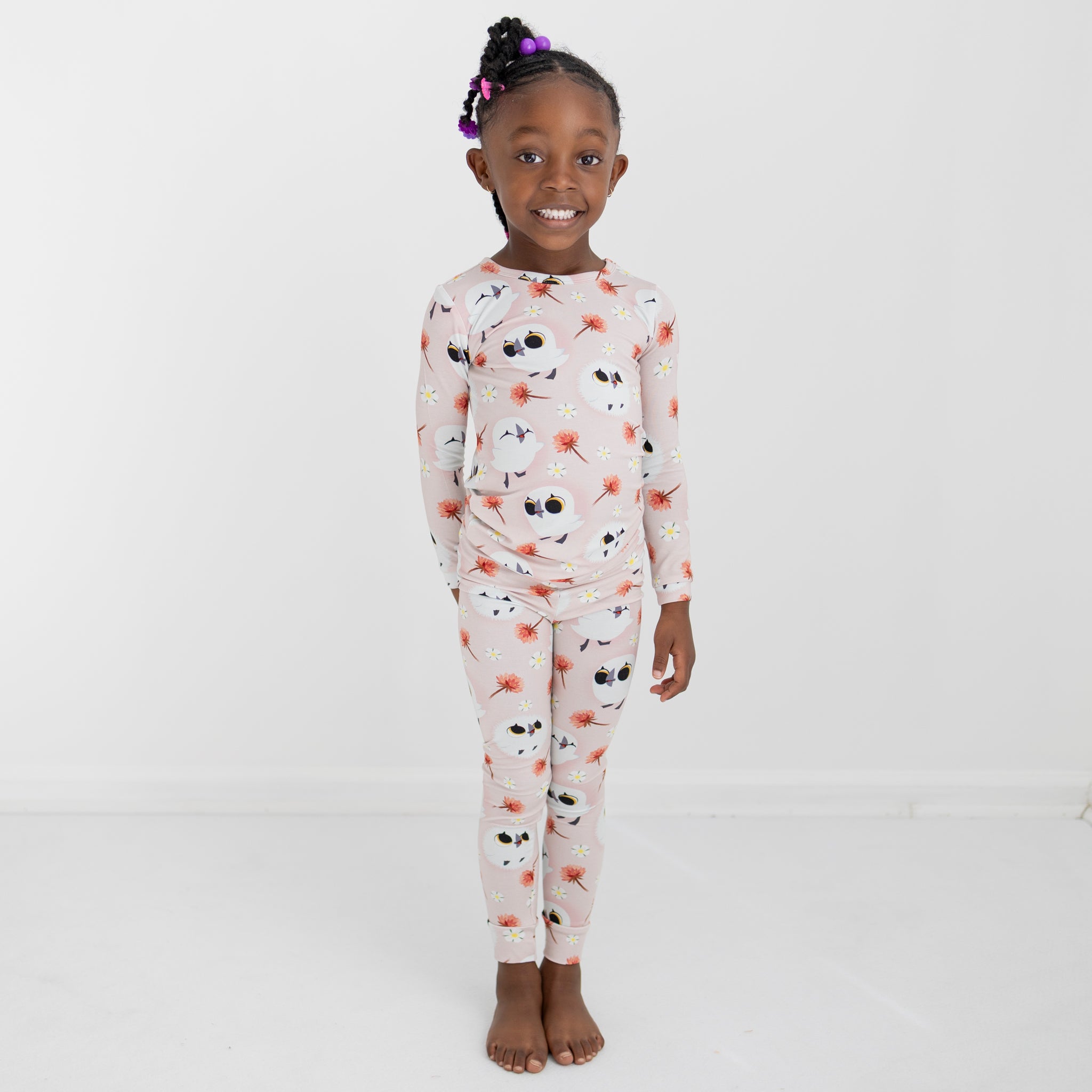 A young girl wears a pink pajama set with a puffin and floral print.