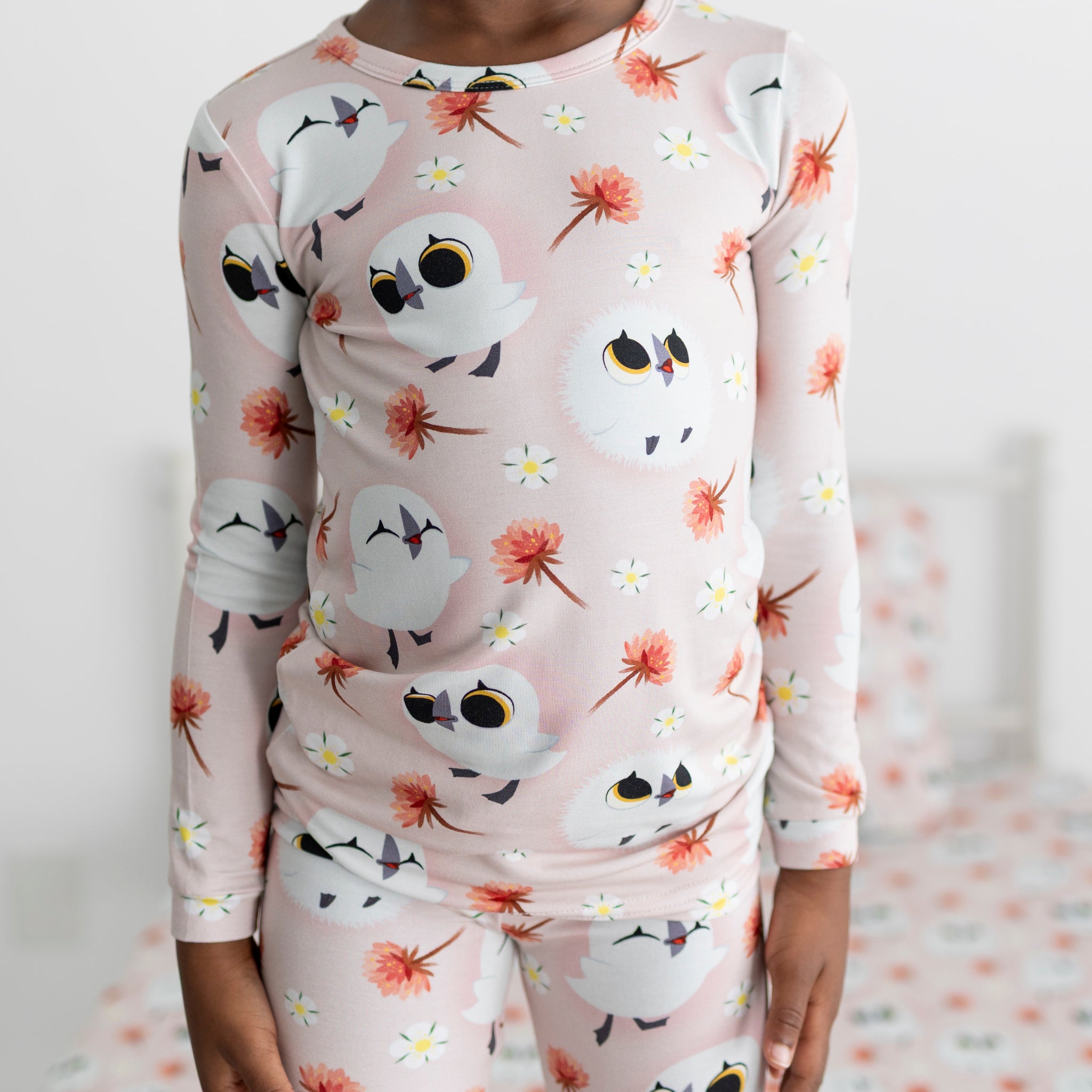 A child wears pink pajamas with a Puffin Rock™ print.