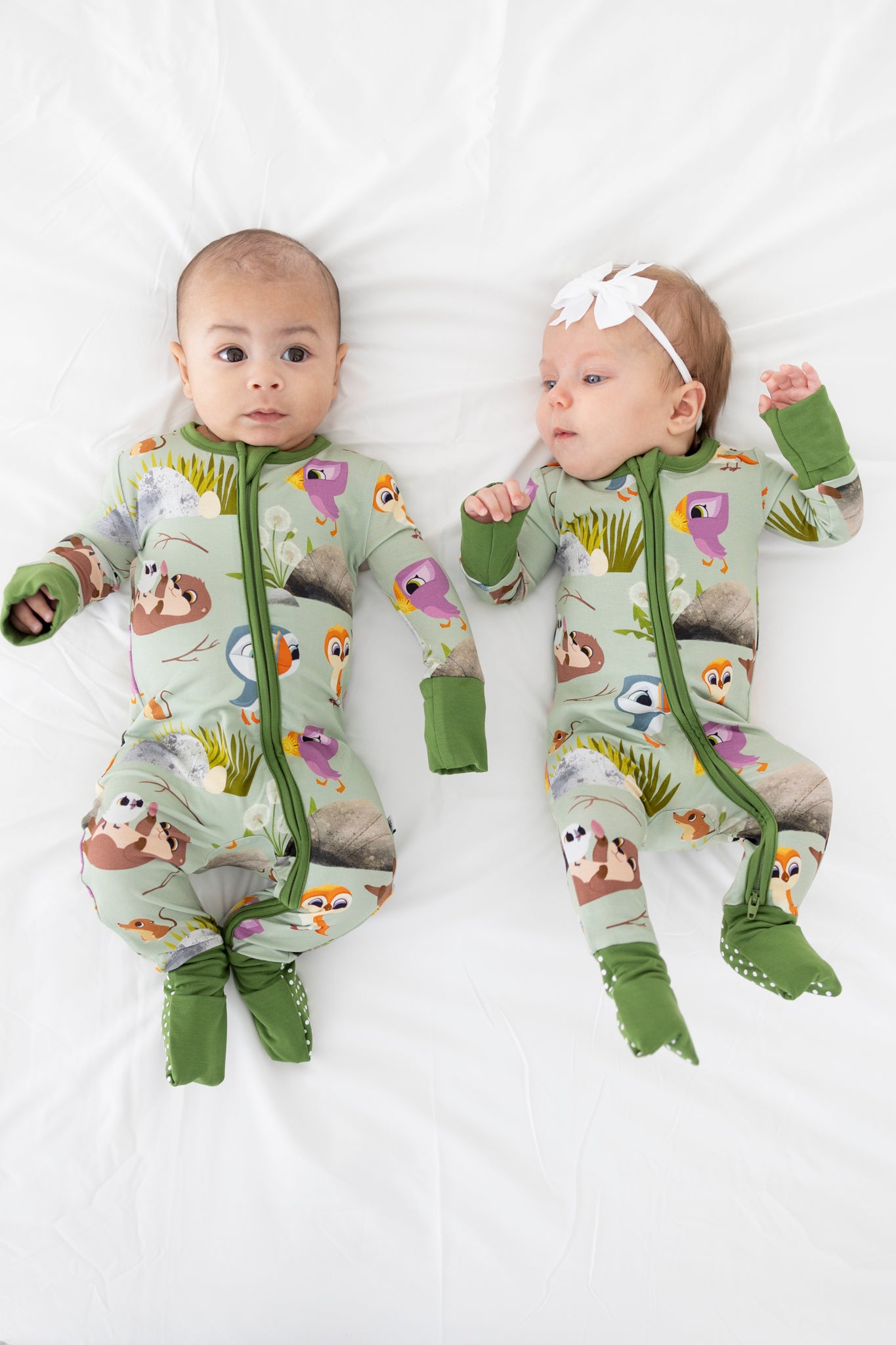 Two babies in green Puffin Rock pajamas with animal prints.
