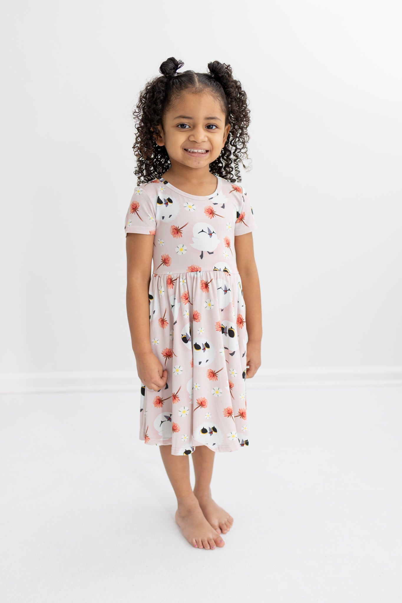 A young girl wears a pink dress with a puffin print.