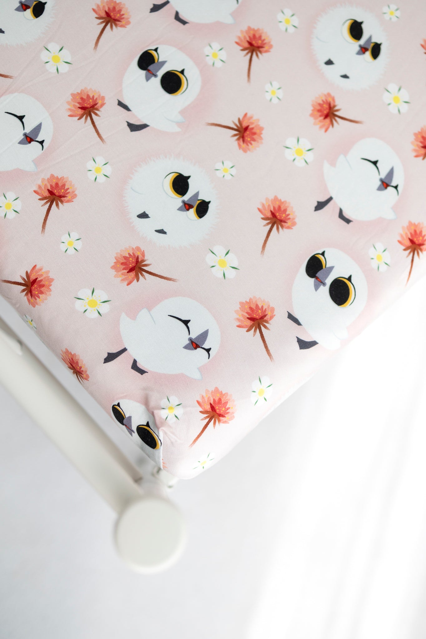 A pink twin sheet with a pattern of white cartoon puffins and orange flowers.