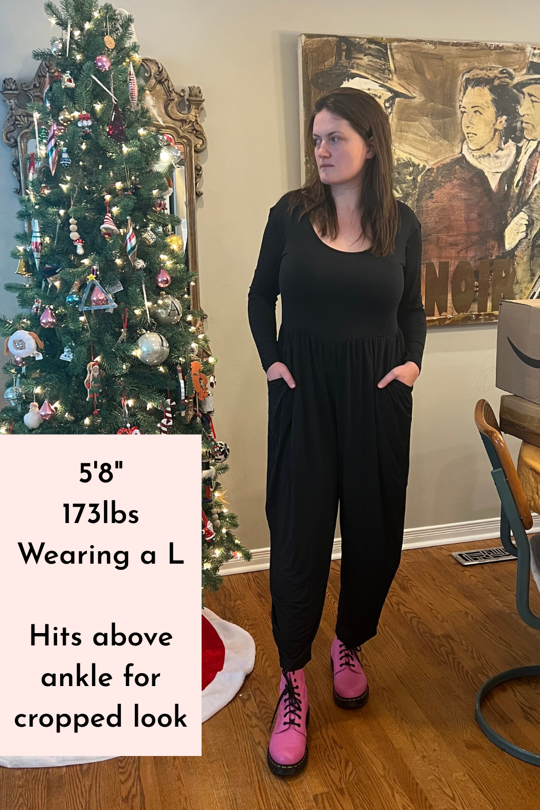 A woman wears a long-sleeve black Tencel Modal romper with a scoop neck and tapered legs.