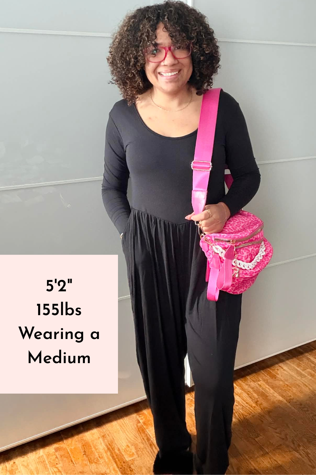 A person wearing a long-sleeve black Tencel Modal romper with a scoop neck and tapered legs.