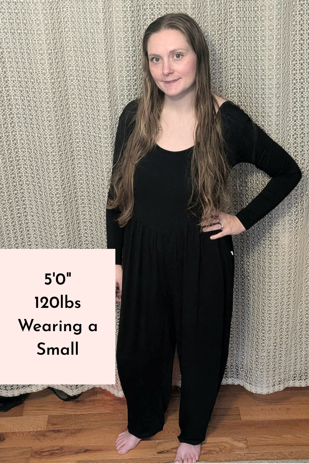 A woman wearing a long-sleeve black adult romper made of Tencel Modal with a scoop neckline.