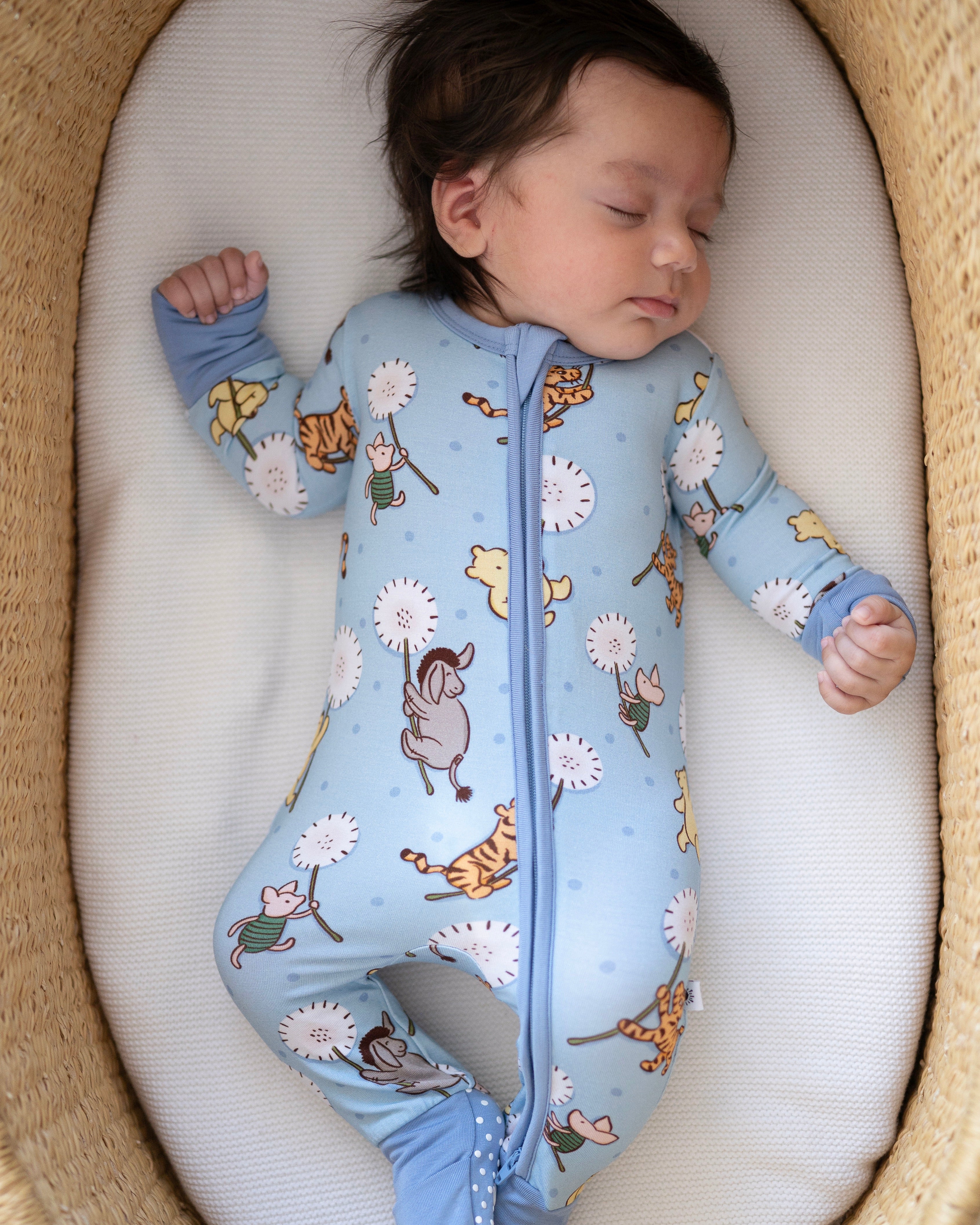 A baby sleeps in a blue pajama set with a Winnie the Pooh print.