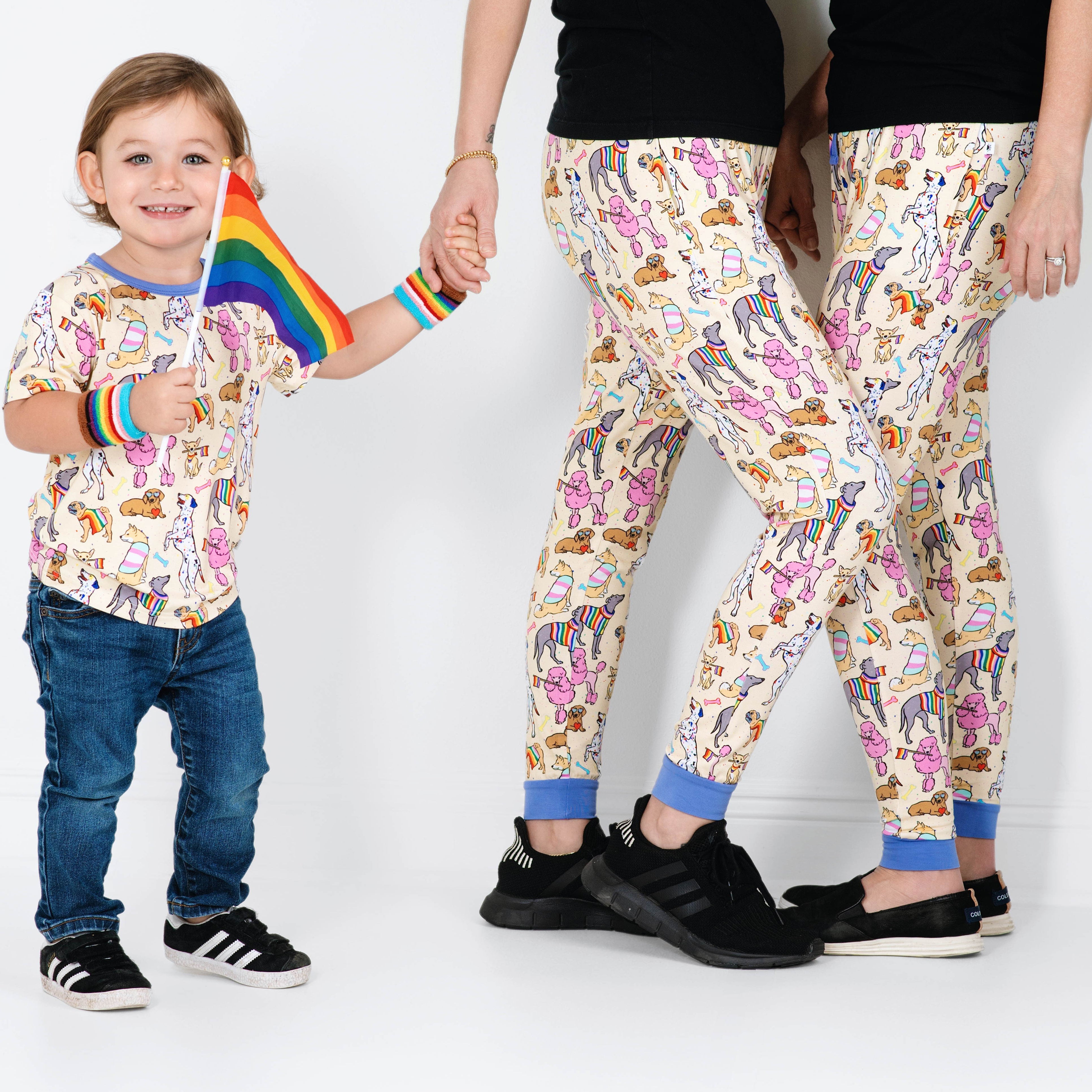Adult joggers with a playful print of dogs wearing rainbow sweaters and holding pride flags.