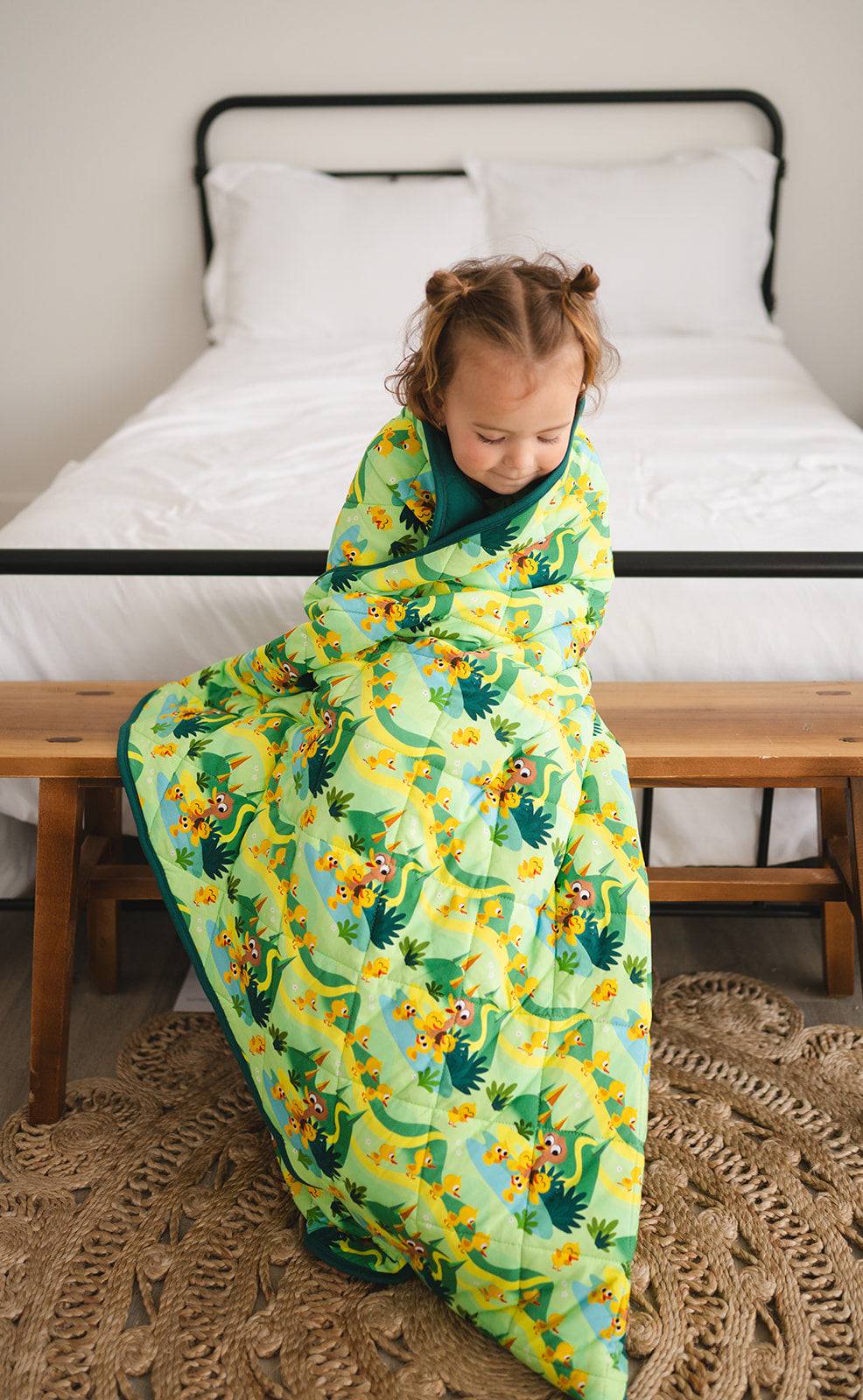 A young child wrapped in a green blanket with a 5 Little Ducks print.