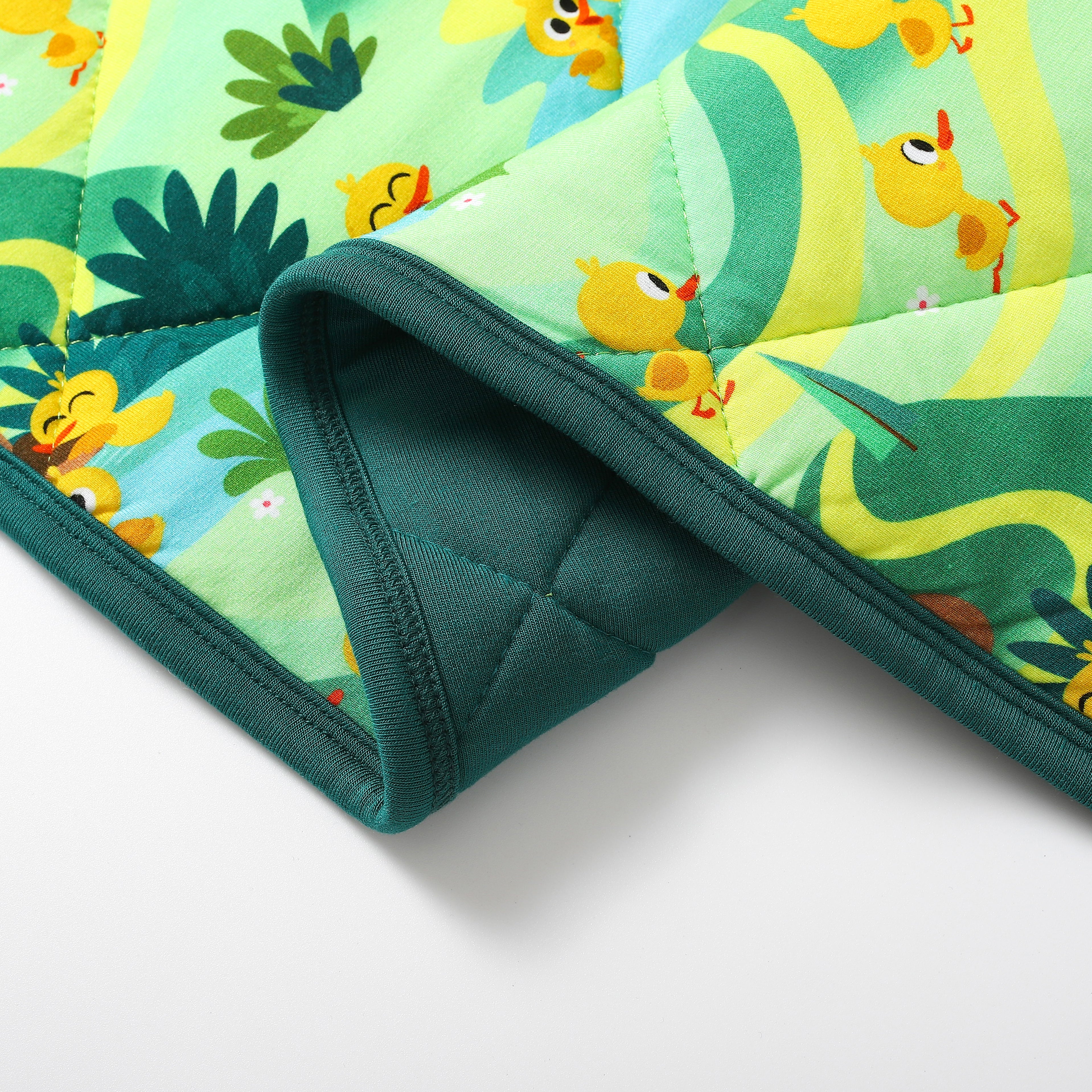 A quilted bamboo couch cover with a "5 Little Ducks" print and dark green trim.