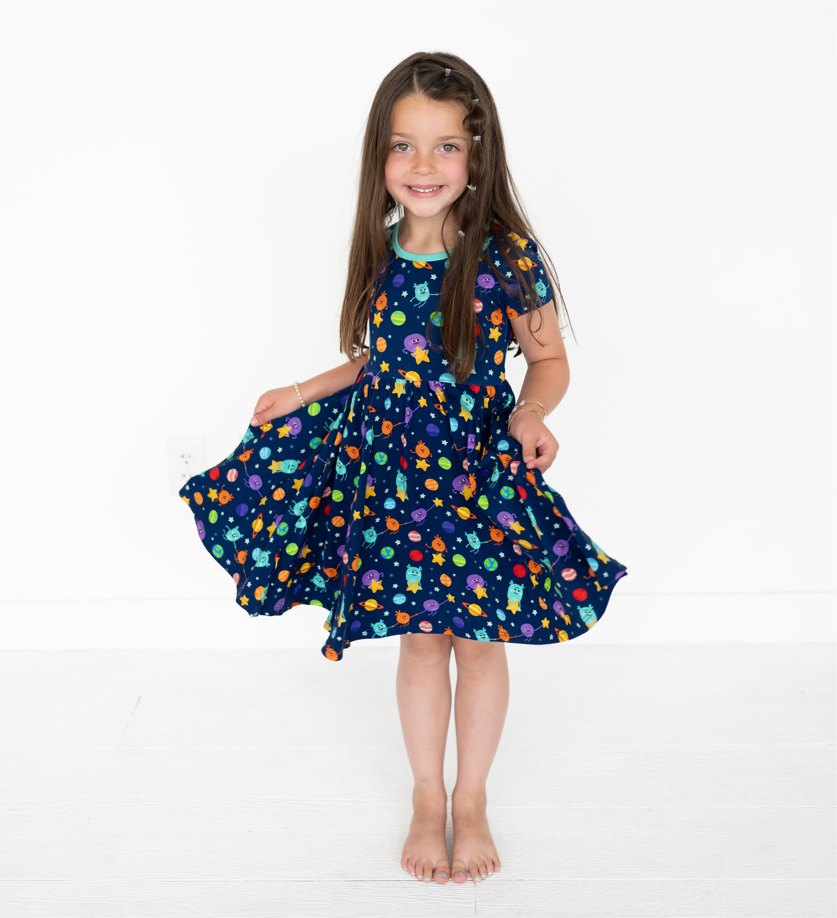 A young girl in a navy blue dress with a space-themed print.