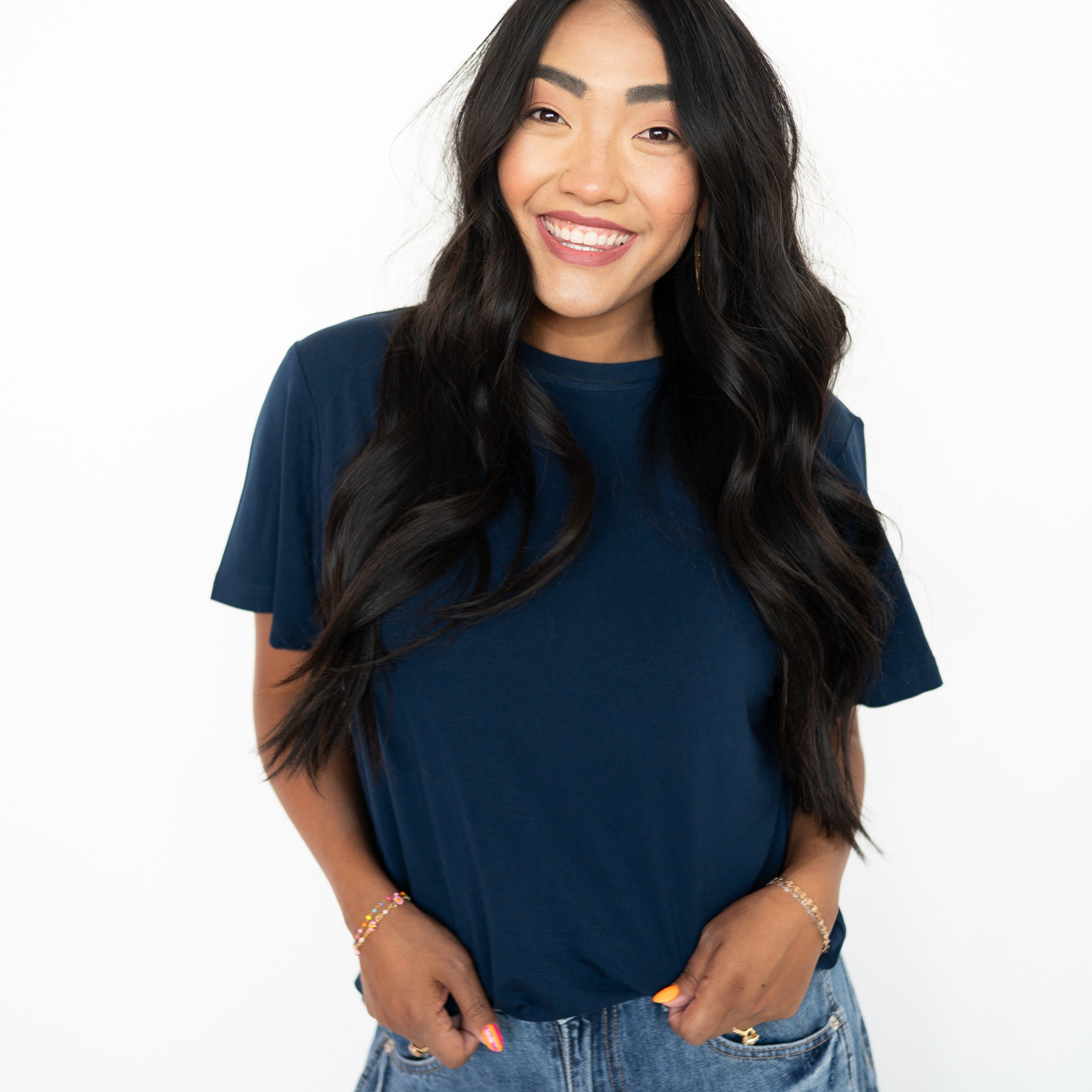 A woman wears a navy oversized bamboo t-shirt and denim jeans.