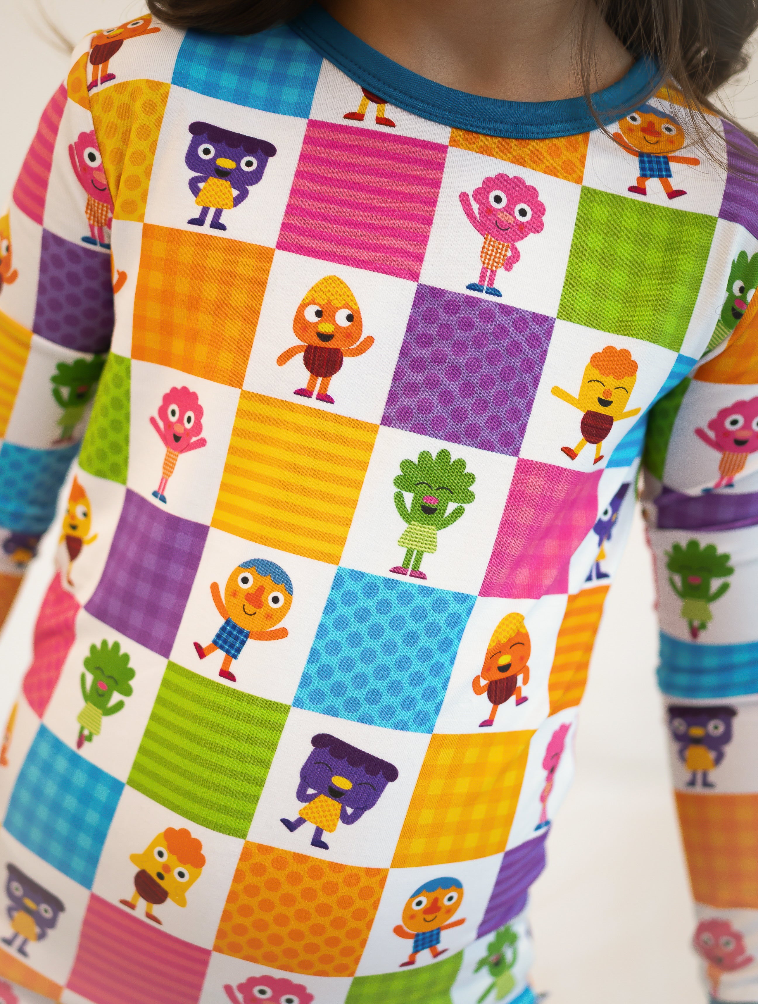 A child's long-sleeved pajama top with a colorful checkerboard pattern featuring cartoon characters.