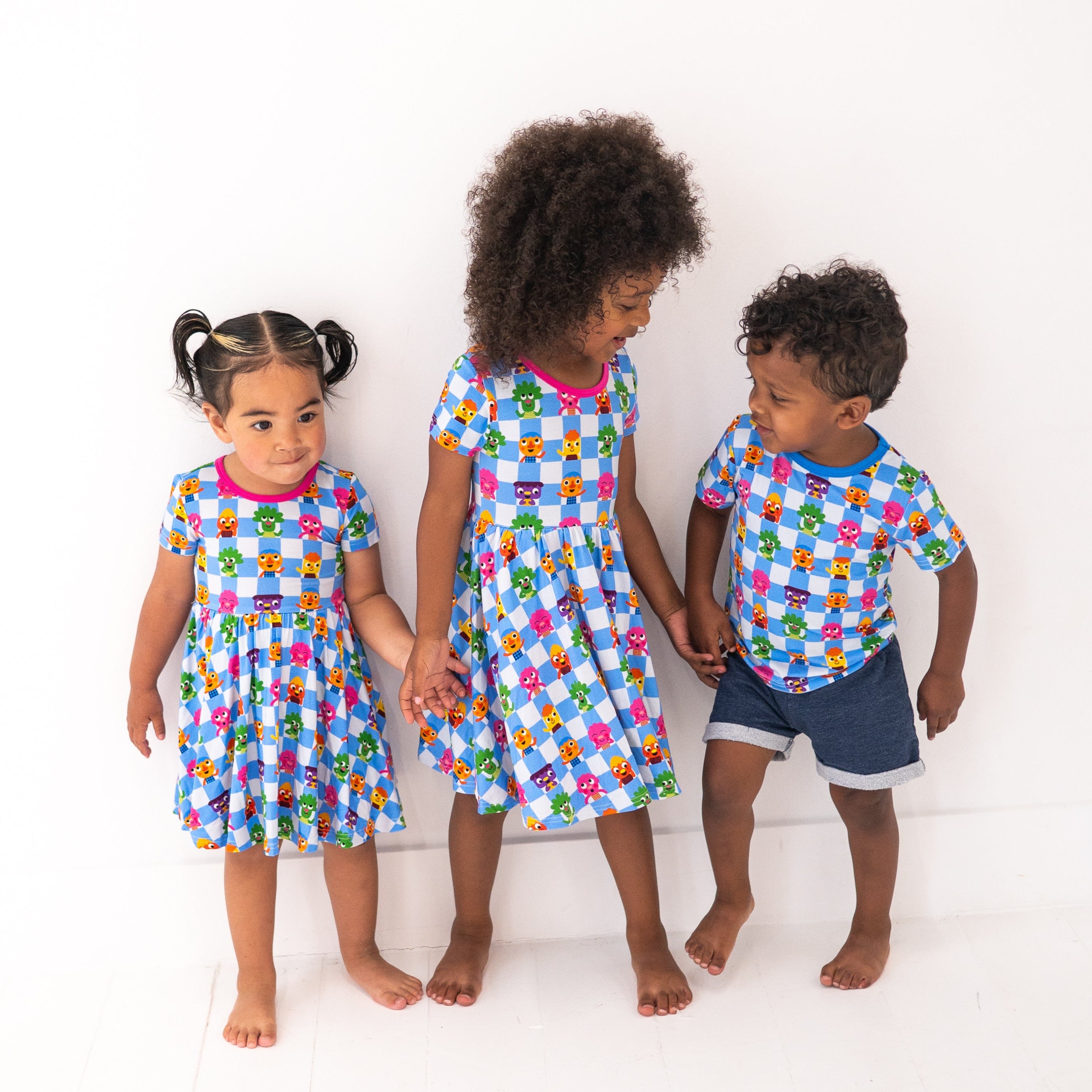 Three children in matching blue checkered outfits with cartoon characters.