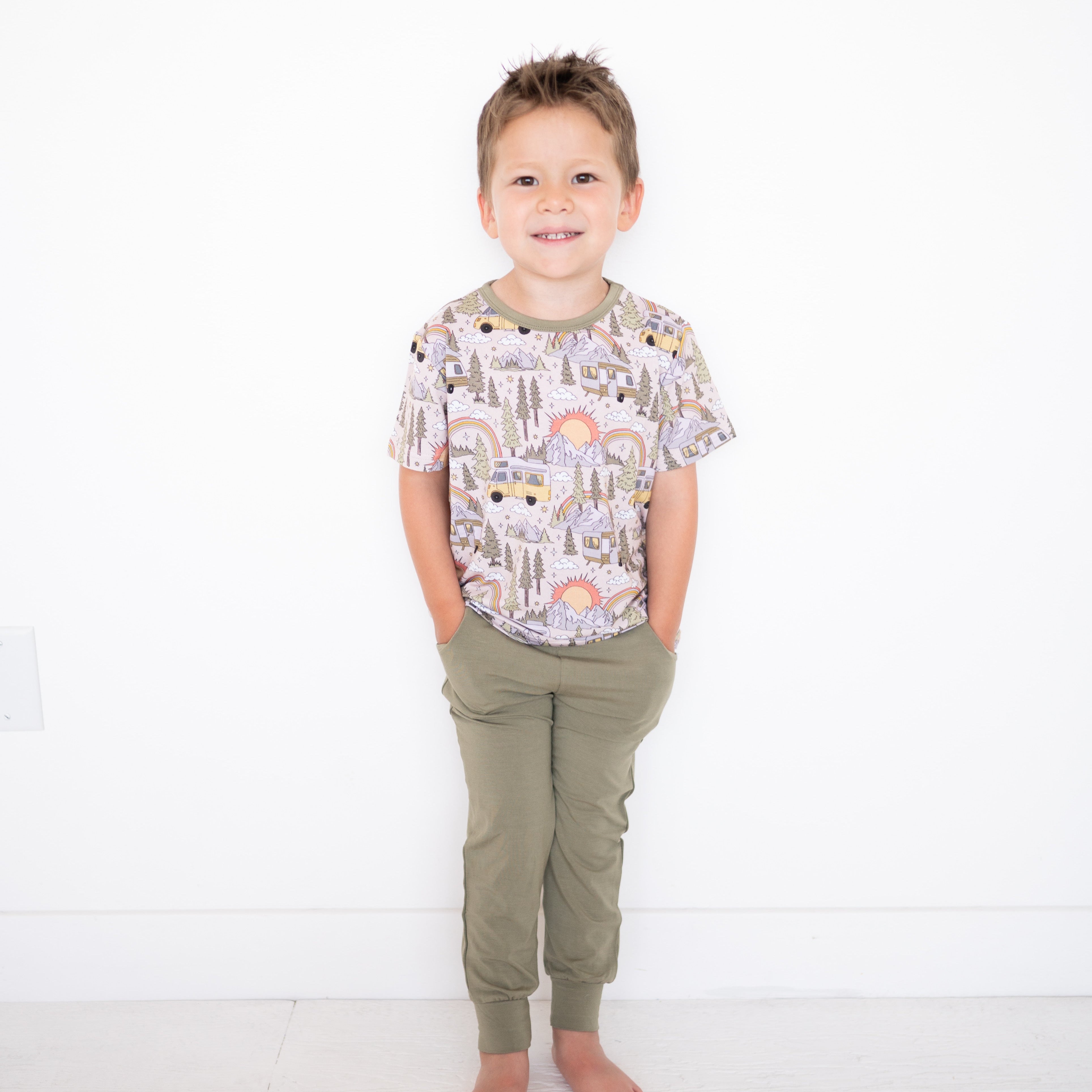 A young boy stands in a vintage green jogger with his hands in his pockets.