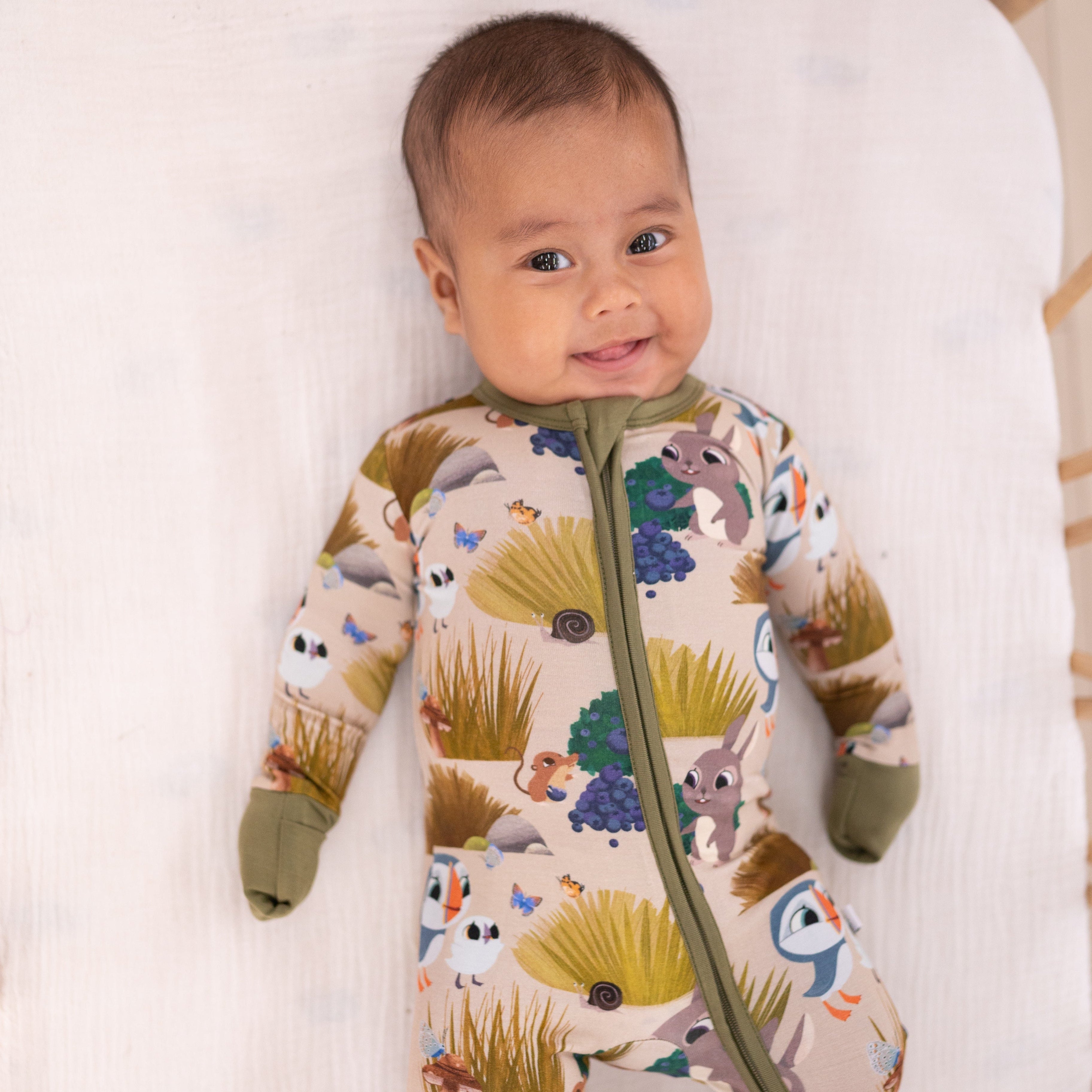 A baby wearing a tan bamboo pajama set with a Puffin Rock™ print.
