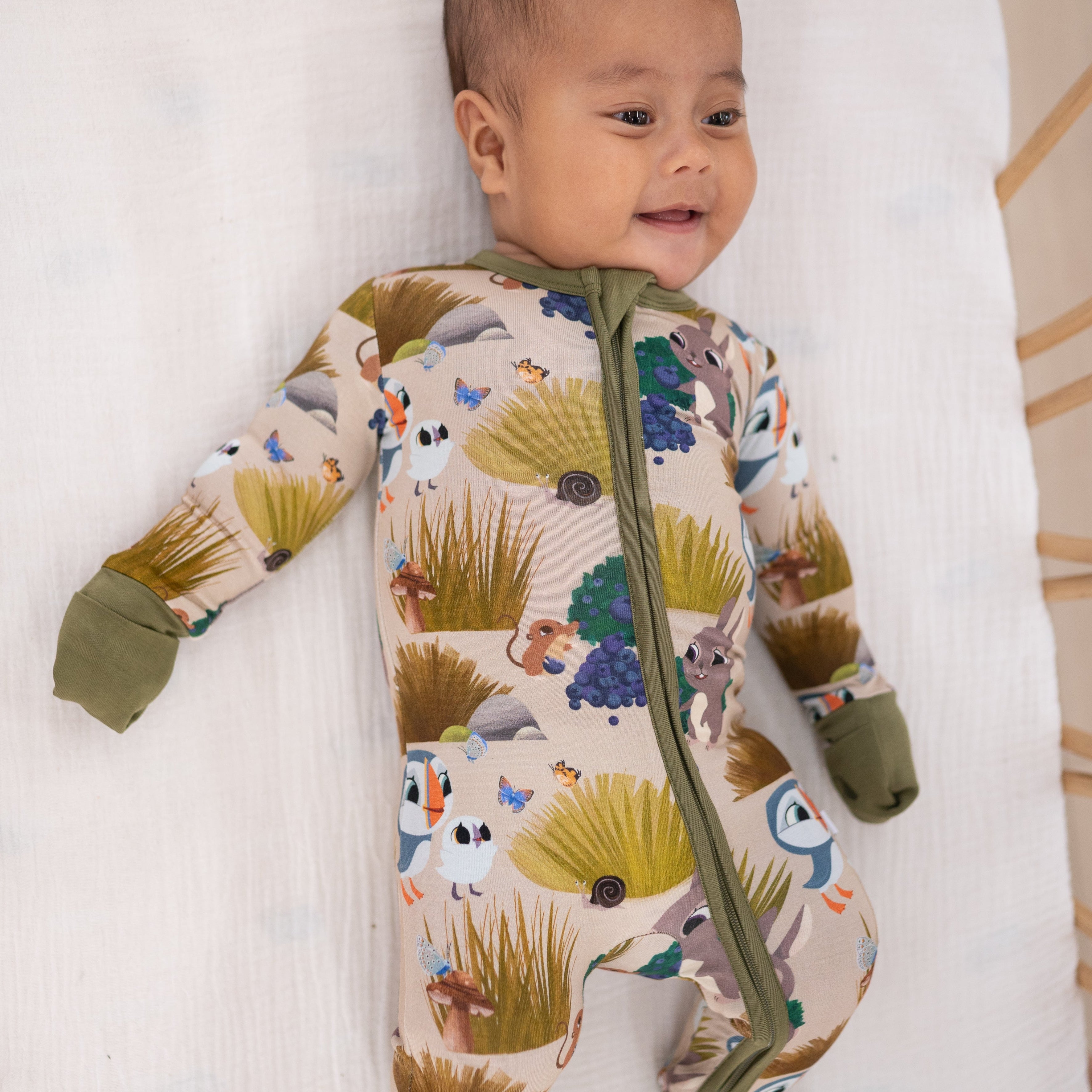 A baby wears a tan bamboo pajama set with a Puffin Rock print.