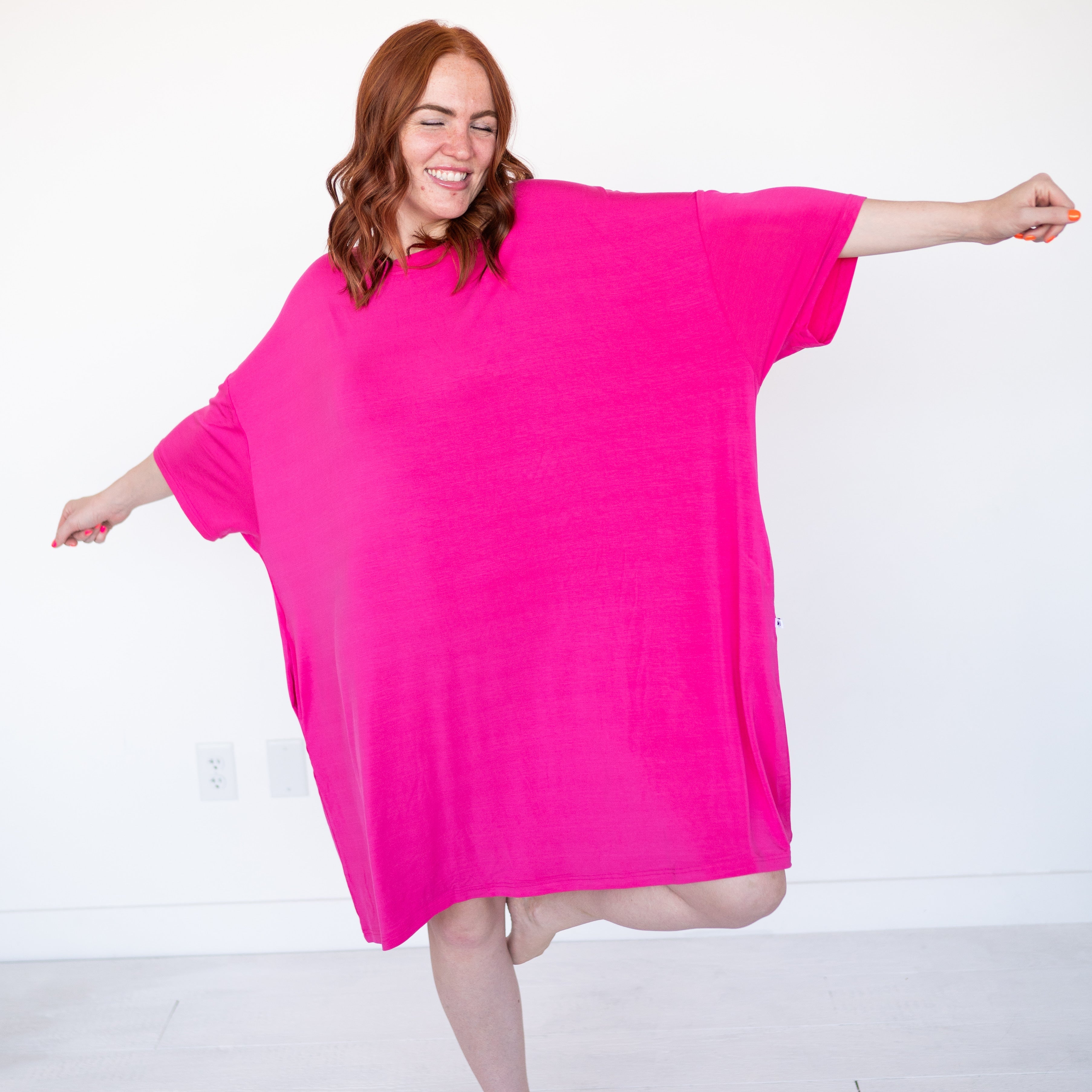 A woman in a pink mega sleep tee with her arms outstretched.