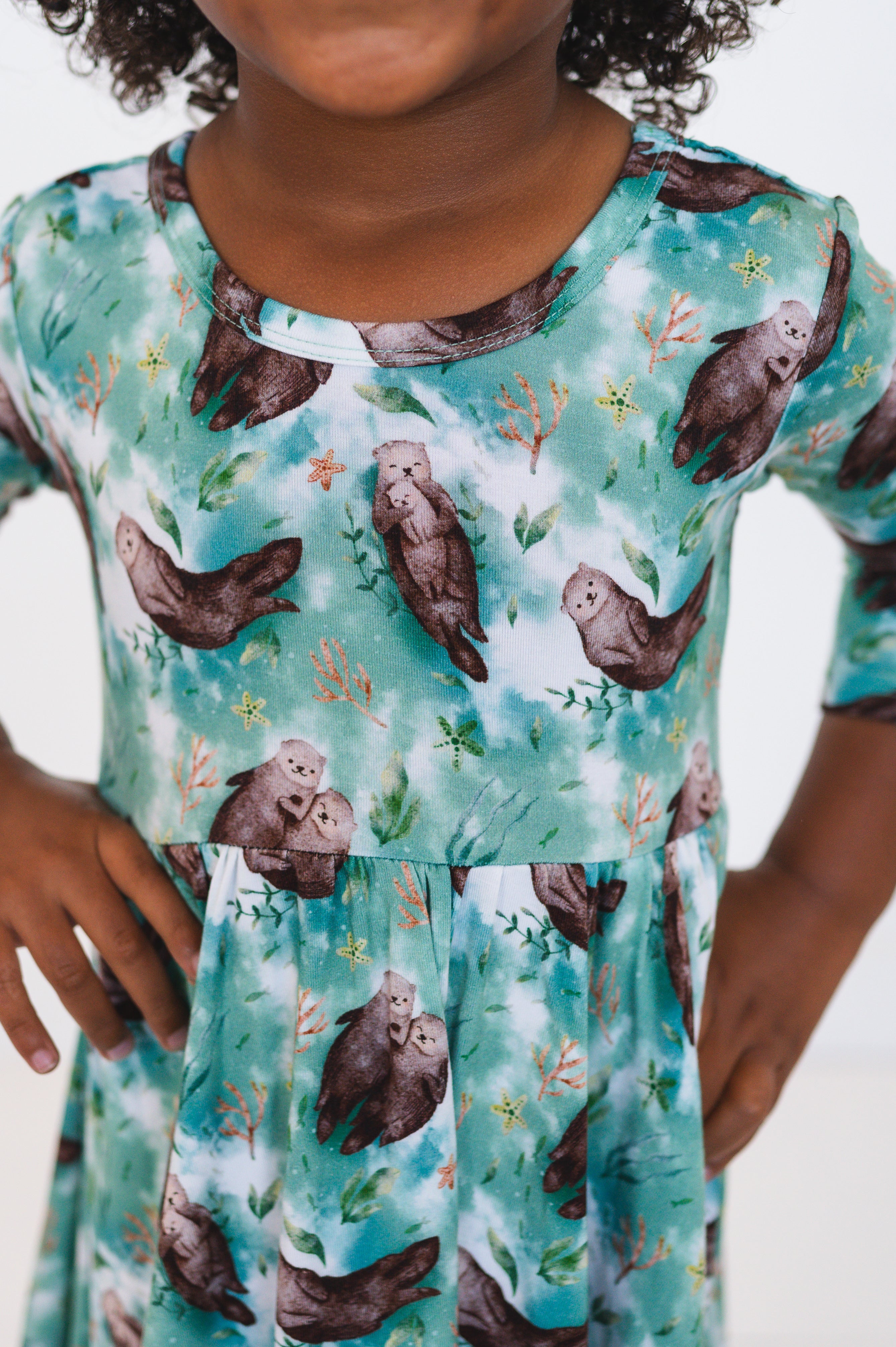 A girl wears a 3/4 sleeve dress with an otter print.