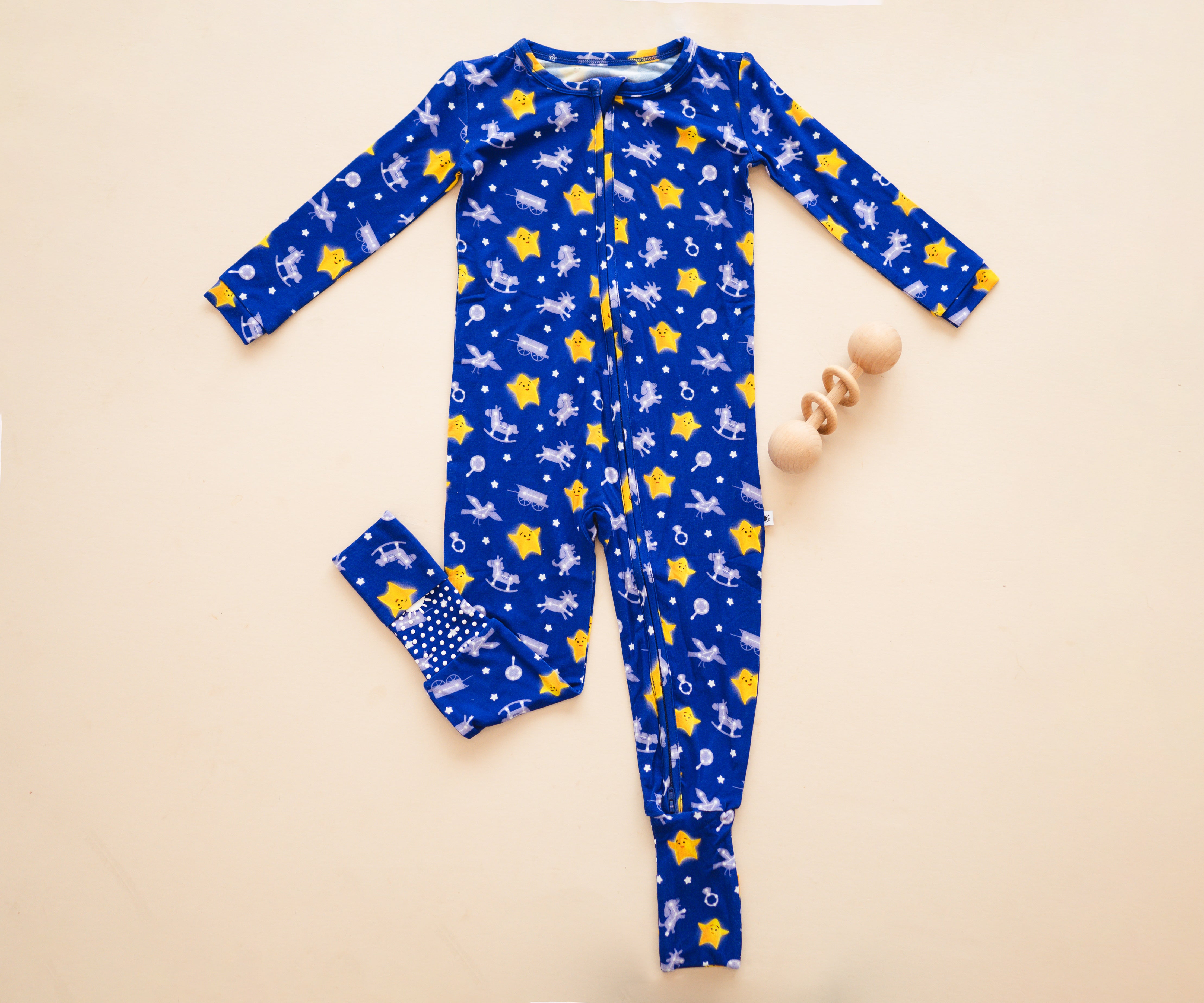 Blue bamboo pajamas with yellow stars and rocking horses, and a wooden rattle.