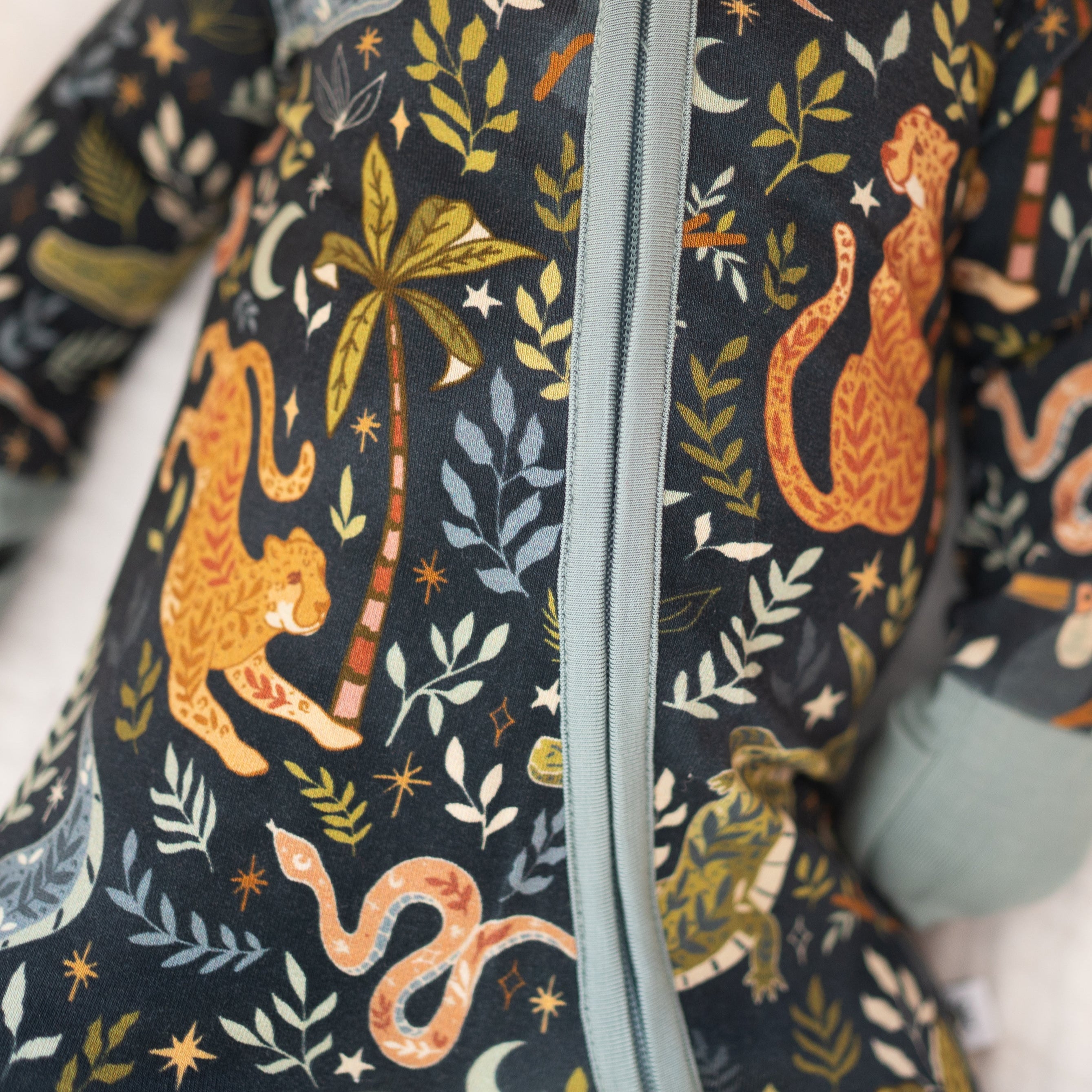 A dark blue pajama set with a jungle print featuring leopards, snakes, and foliage.