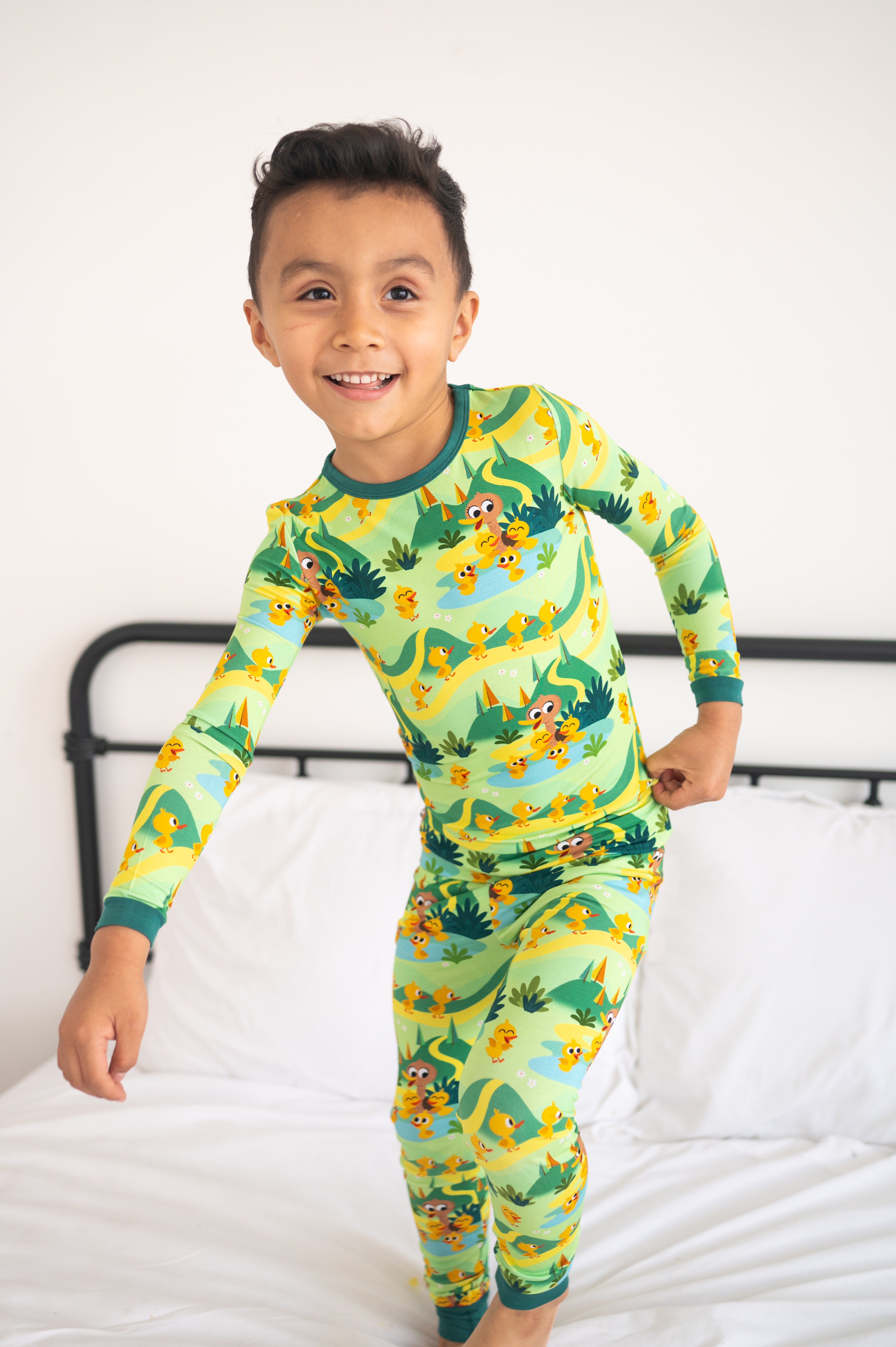 A young boy smiles in green pajamas with a duckling print.
