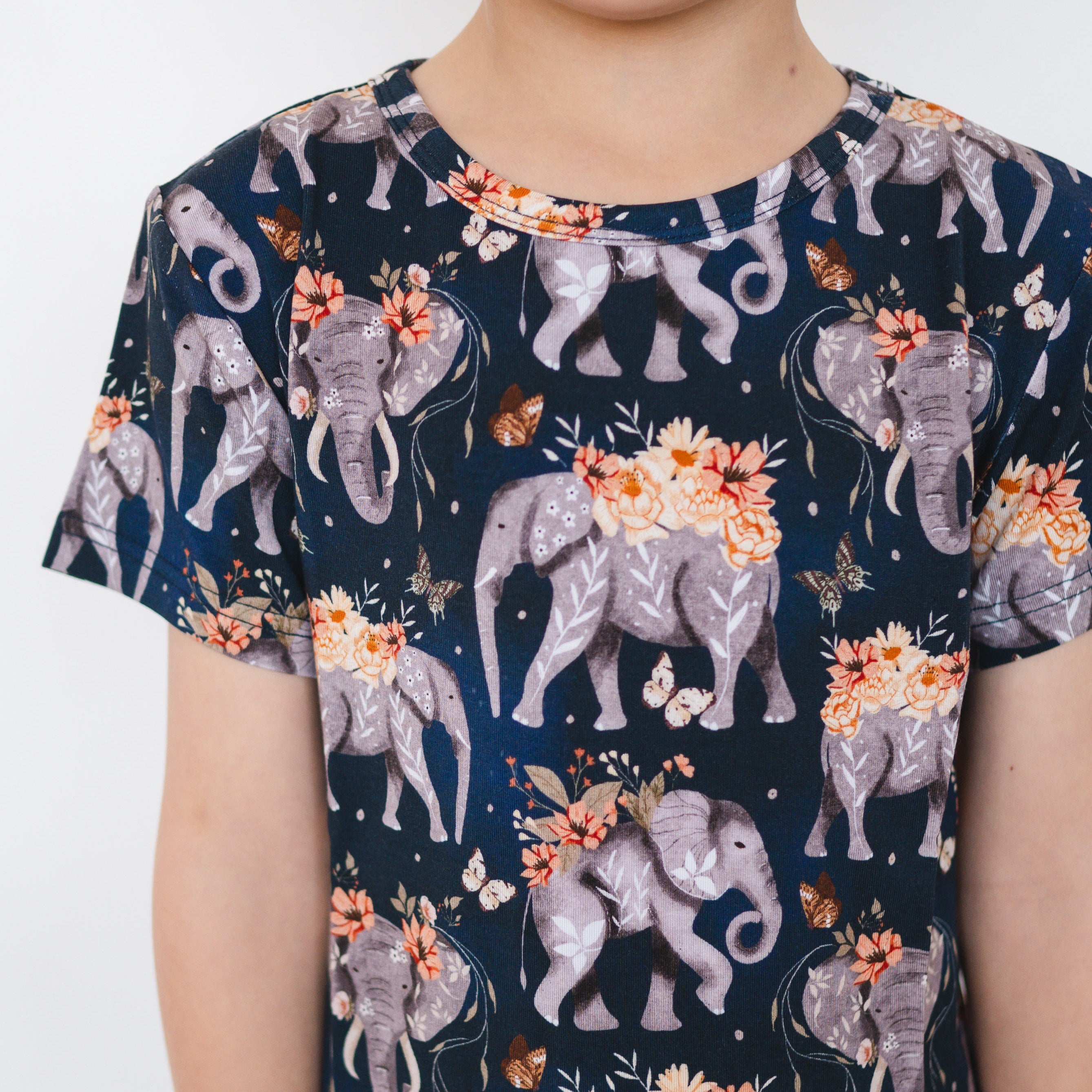 T-shirt with a dark blue background and a pattern of grey elephants with flowers and butterflies.