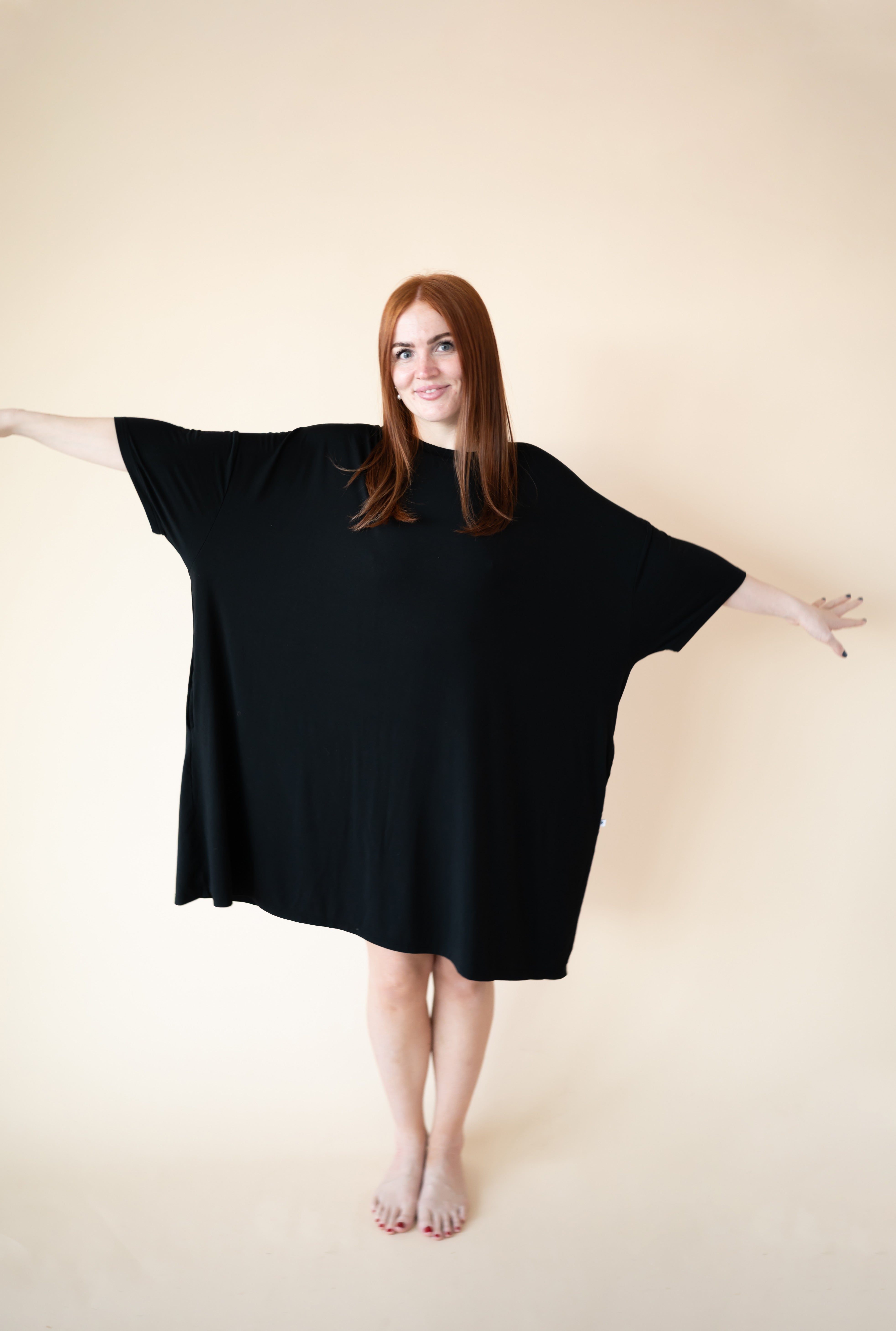 A woman models an oversized, black Tencel Modal sleep tee with wide sleeves and a loose fit.