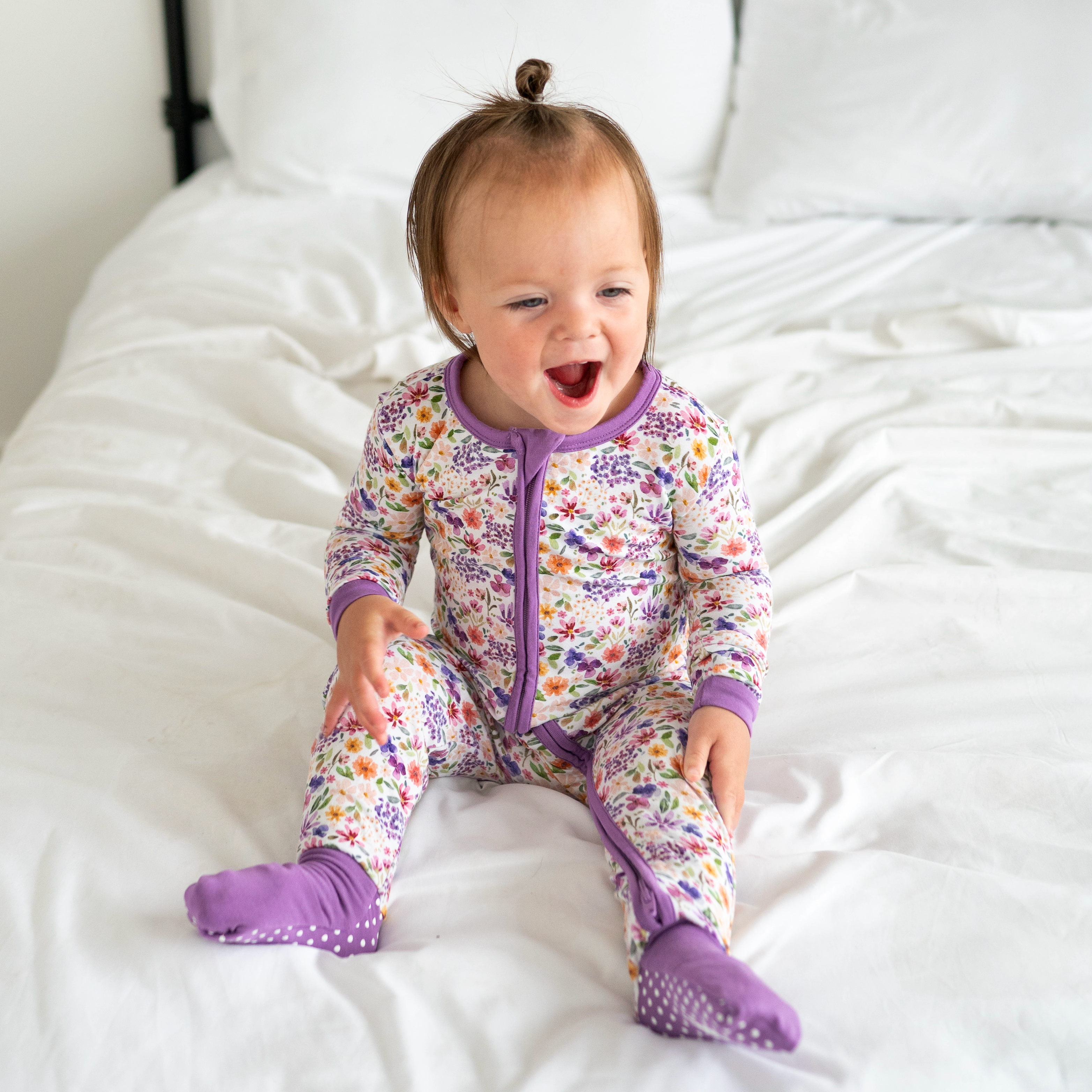 Baby in a floral bamboo pajama set with purple trim and footies.