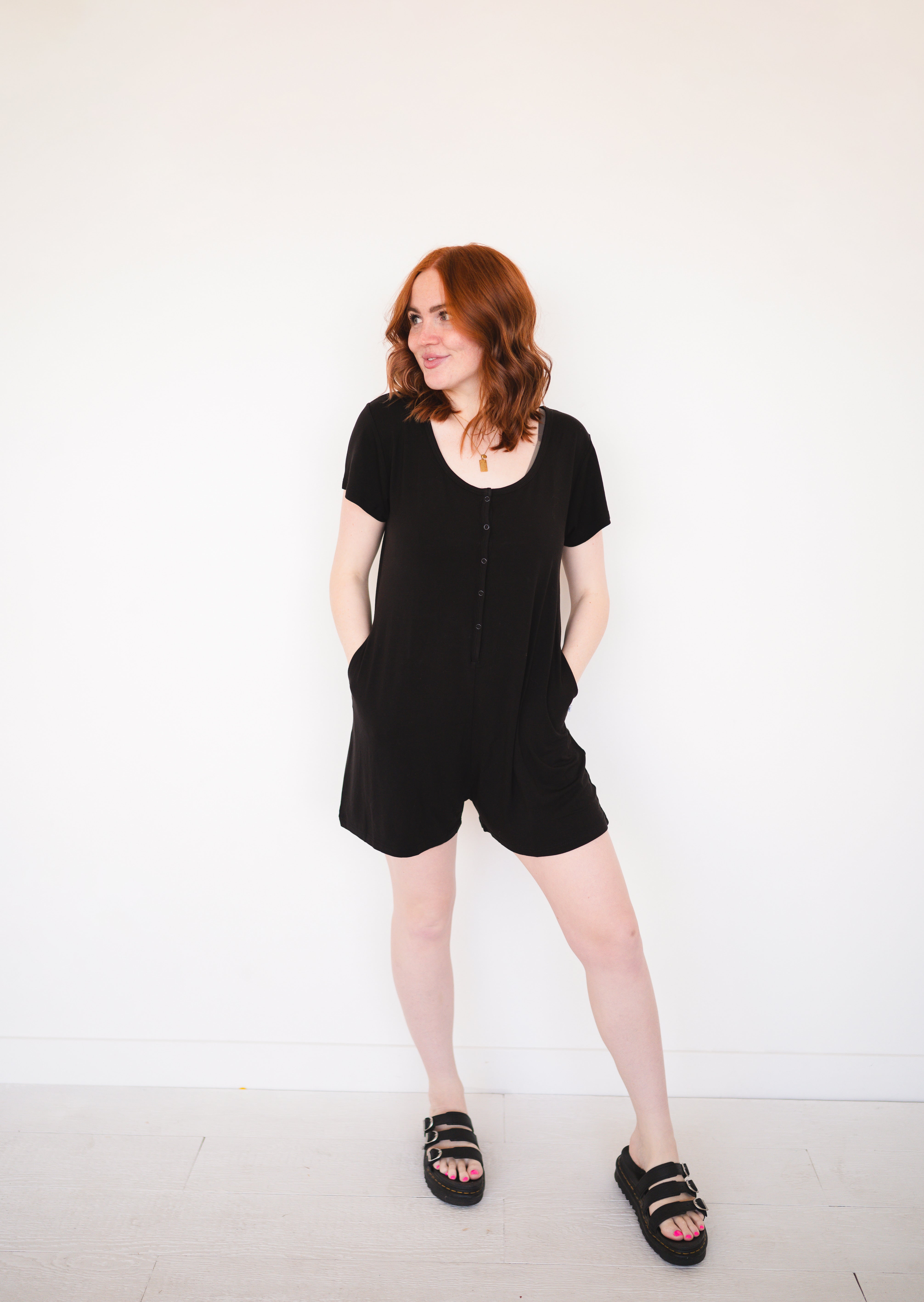 Black short-sleeve romper with button front and pockets.