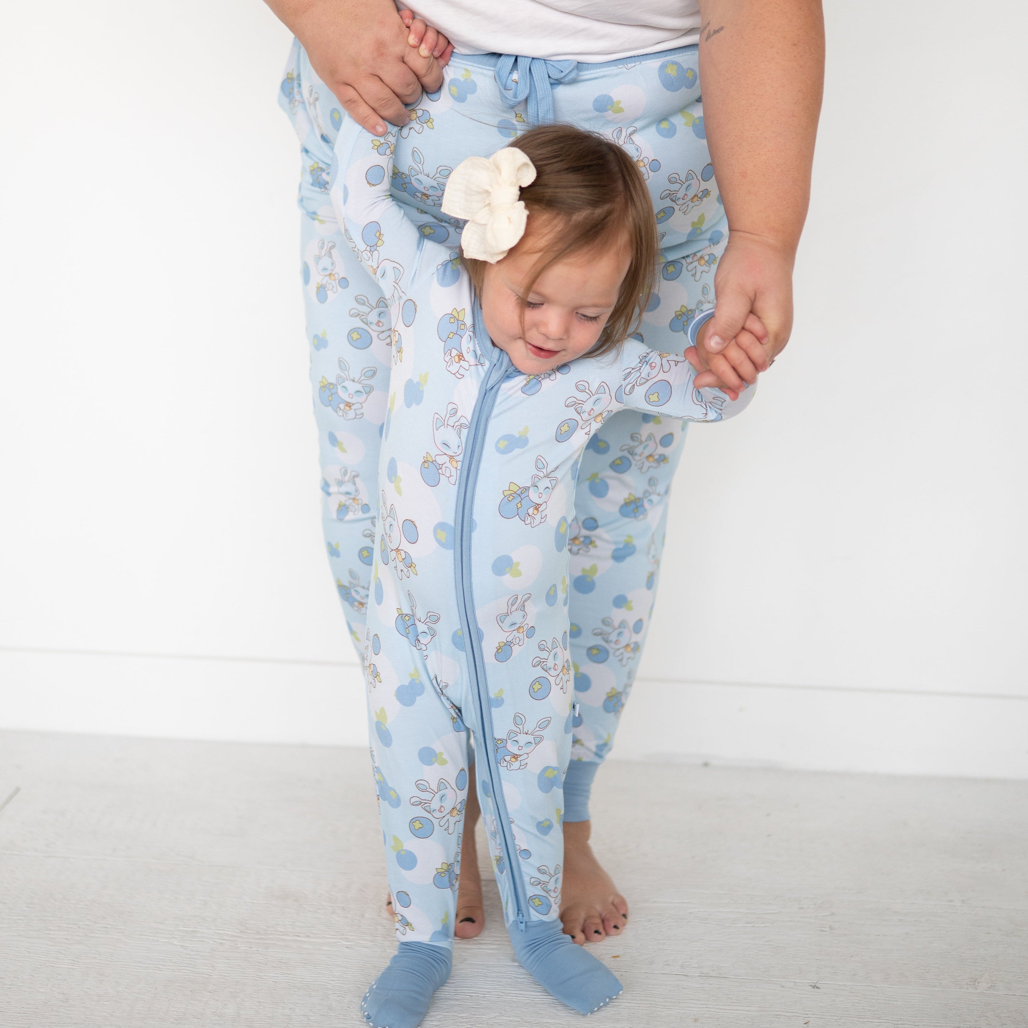 Baby in blue Neopets blueberry print zip pajamas with a white bow.