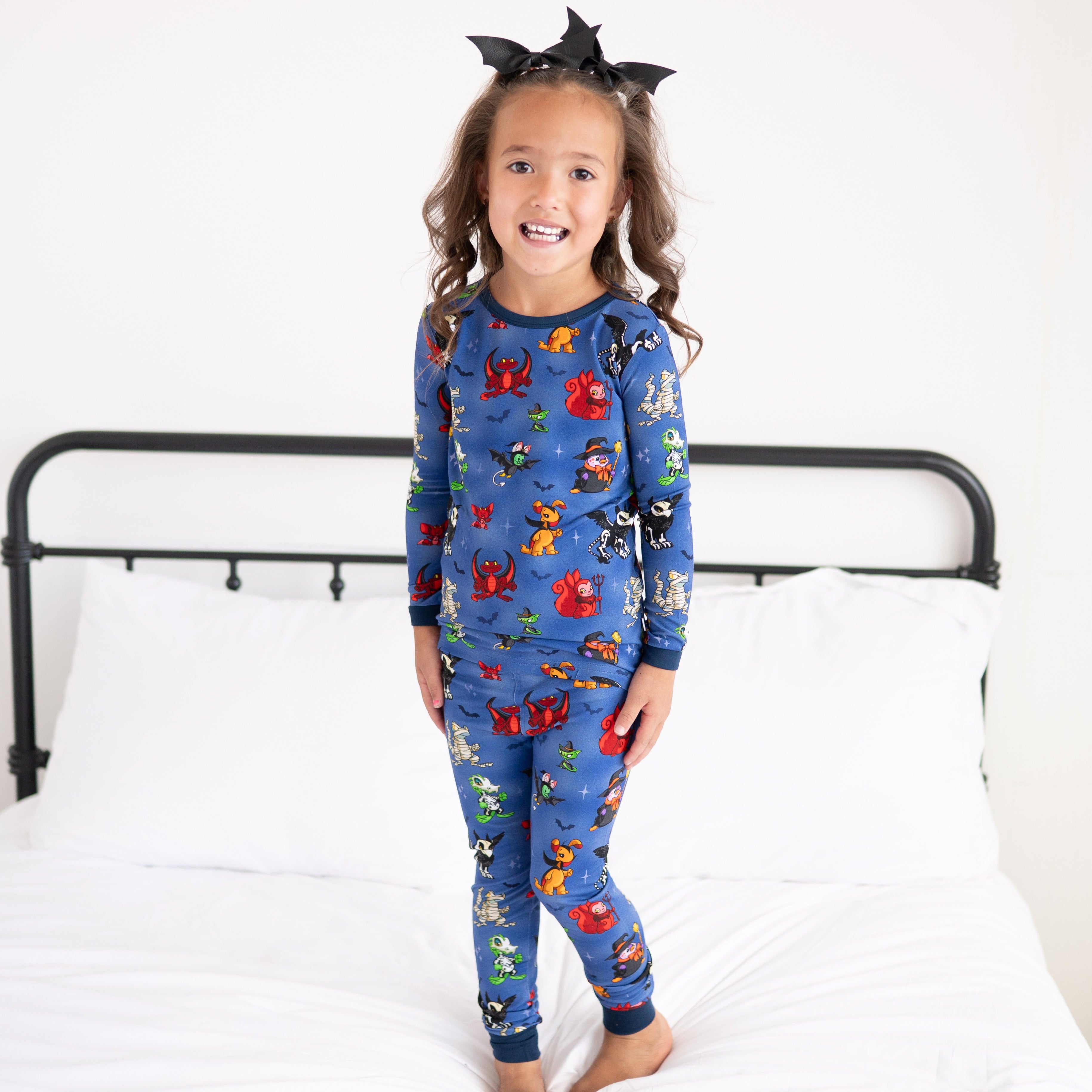 A young girl wears blue Halloween-themed Neopets pajamas and a bat bow.