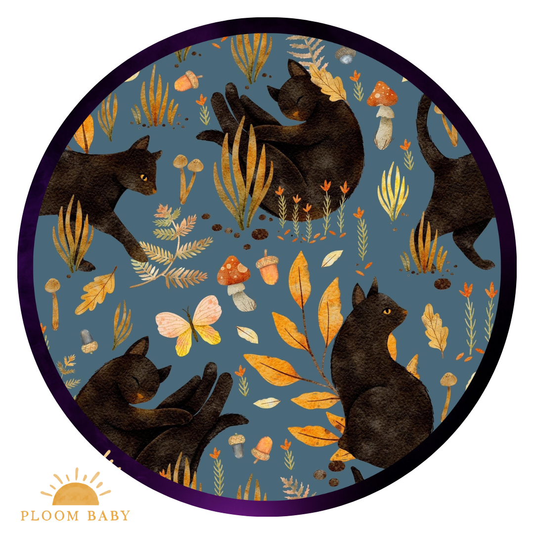 A circular pattern featuring black cats, autumn leaves, mushrooms, and acorns on a blue background.
