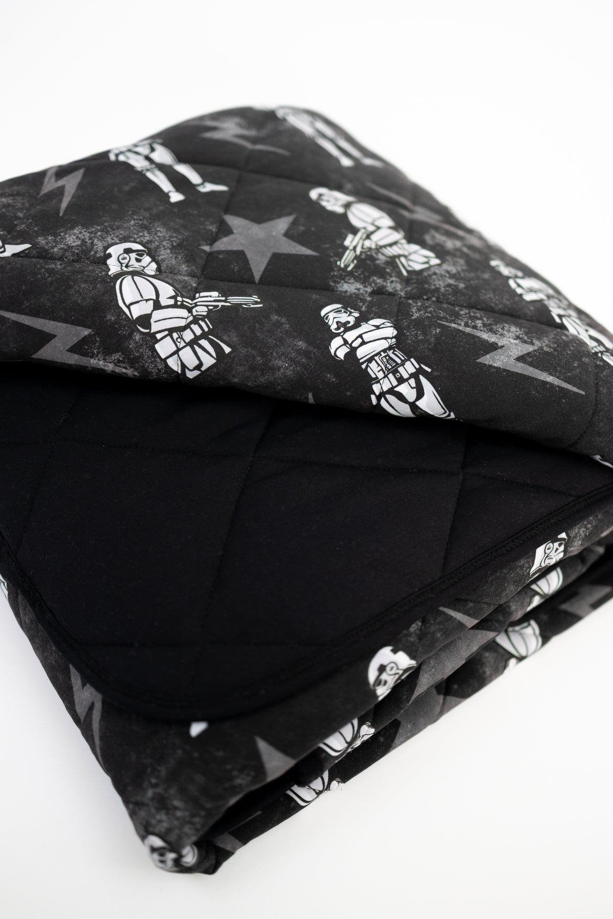 A black quilted blanket with a repeating pattern of white stormtroopers and lightning bolts.